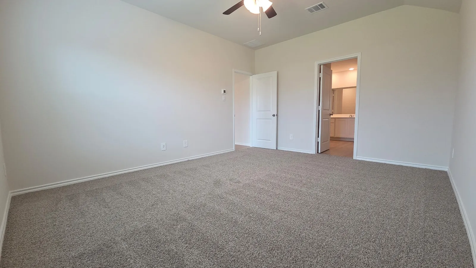 Spacious room featuring neutral carpet flooring, light-toned walls, a ceiling fan, and white trim