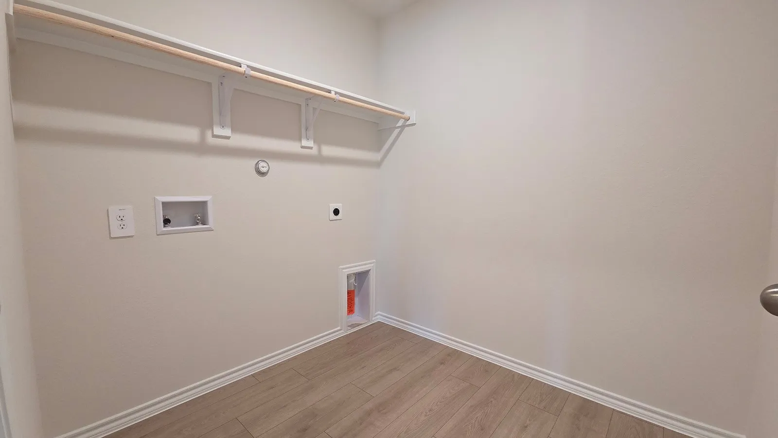 Dedicated laundry space featuring wood-finish flooring, white baseboards, and neutral wall tones