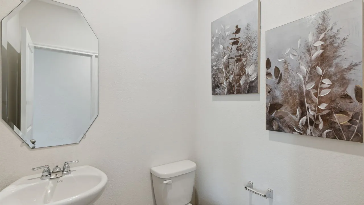 Pedestal sink with chrome fixtures and an octagonal mirror