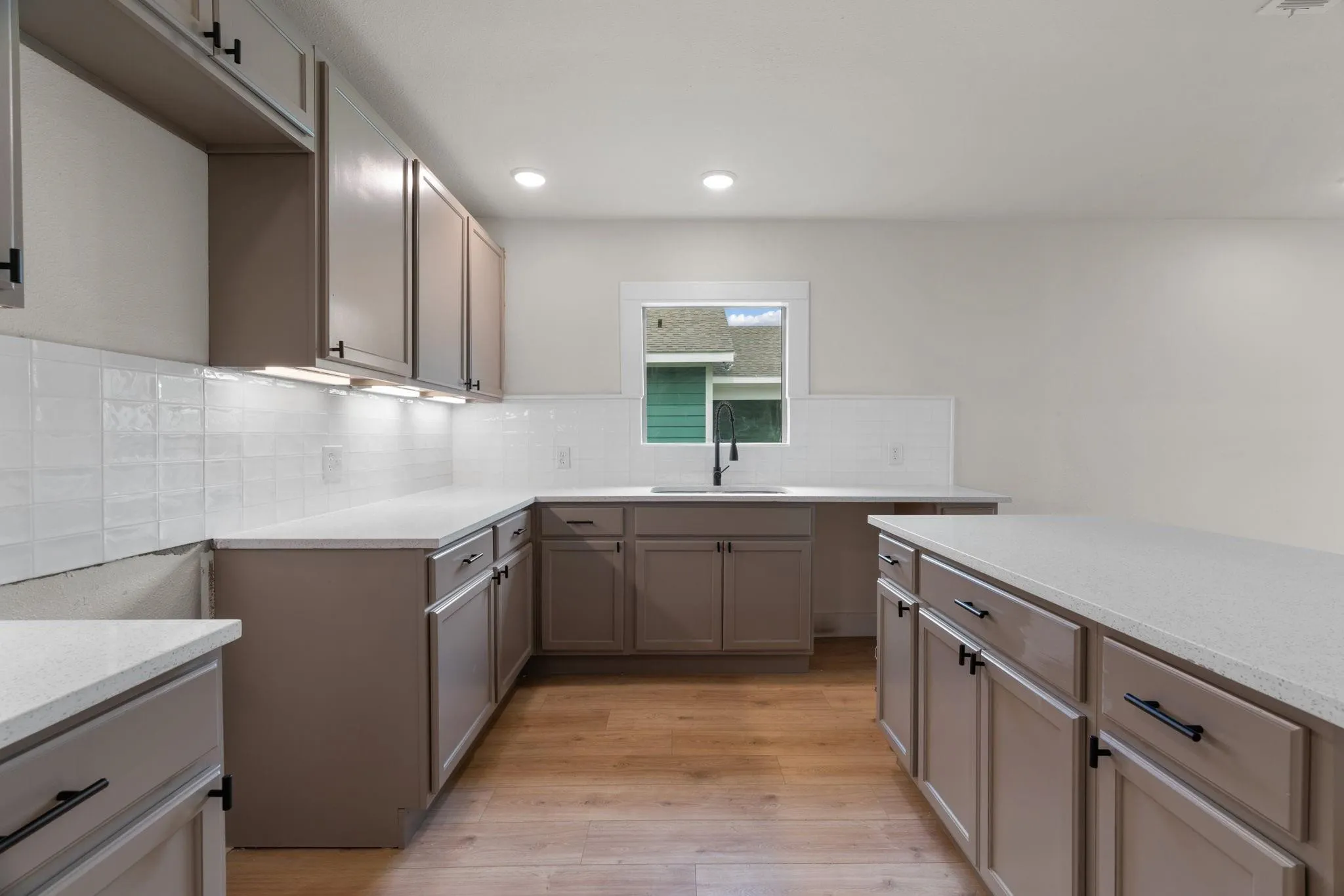 Kitchen featuring a sink, light wood finished floors, backsplash, and recessed lighting