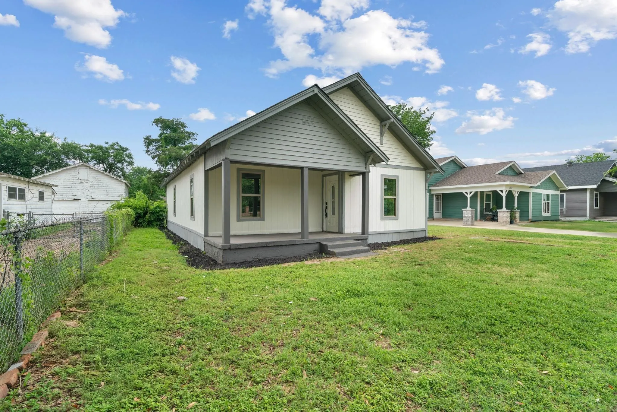 Single-story residence featuring light-colored siding with dark trim accents, a covered front porch, and a gable roofline