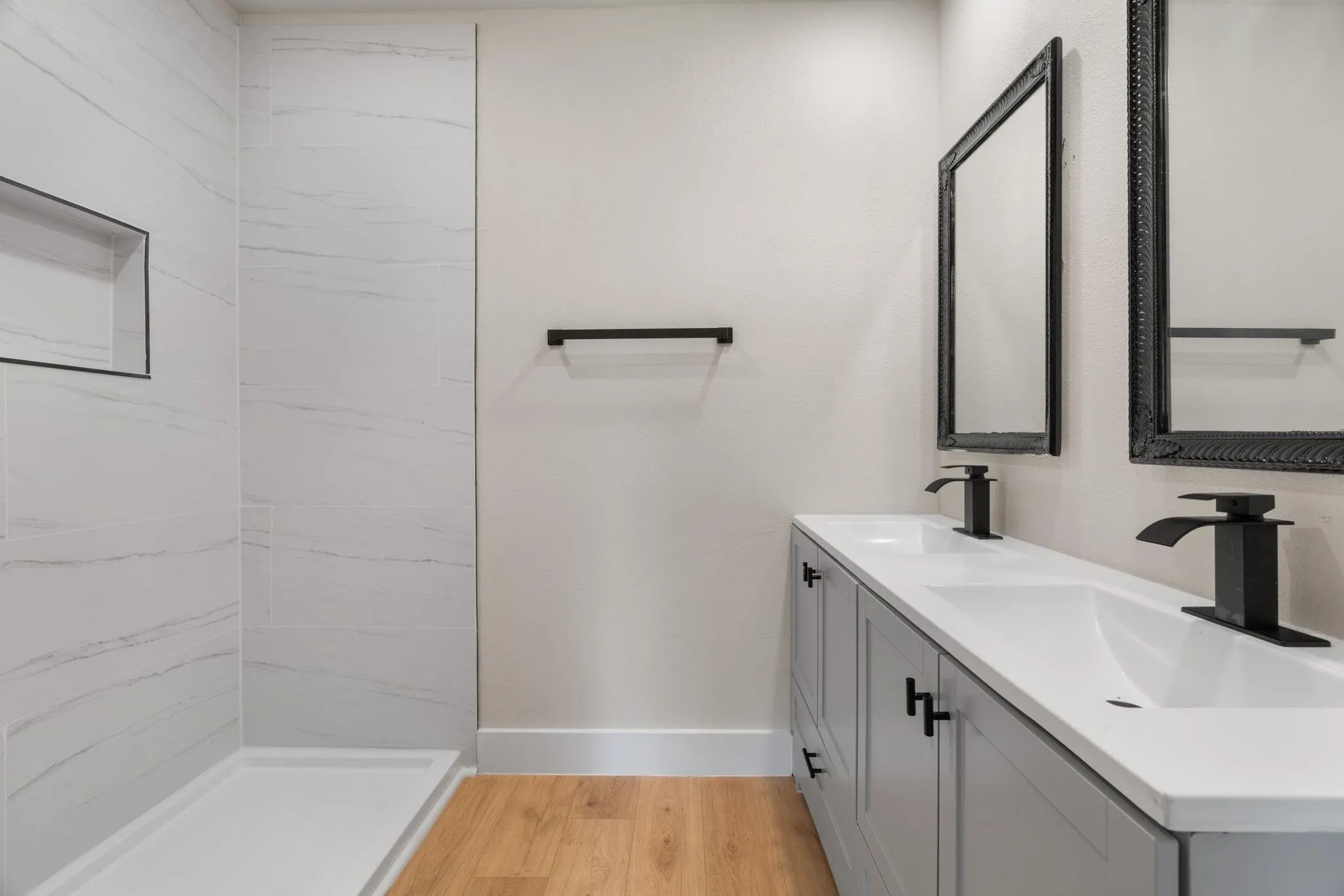Contemporary bathroom featuring a dual vanity with white countertops, matte black faucets, and ornate framed mirrors