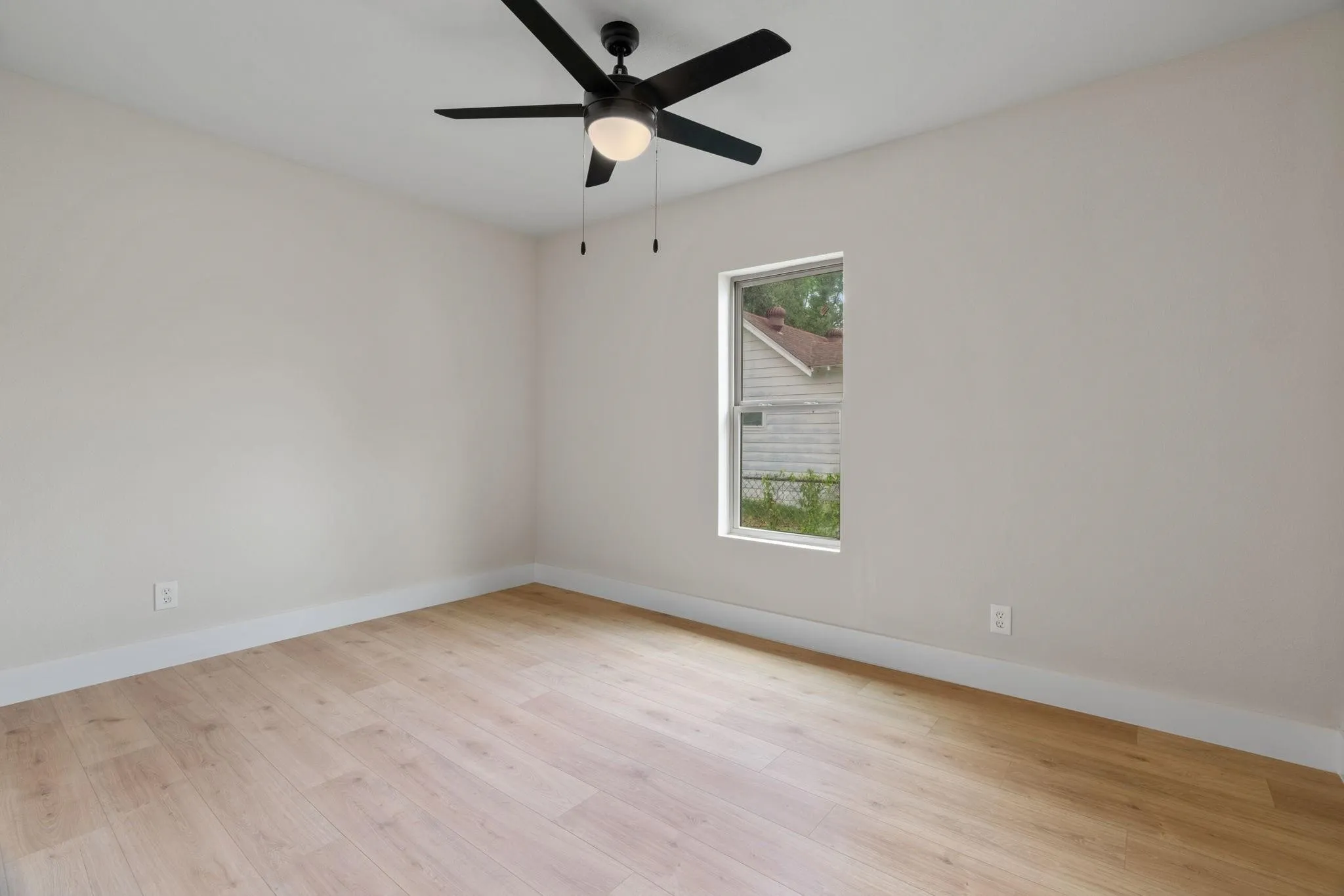 Spacious room featuring wood-finish flooring, white baseboards, and neutral wall tones