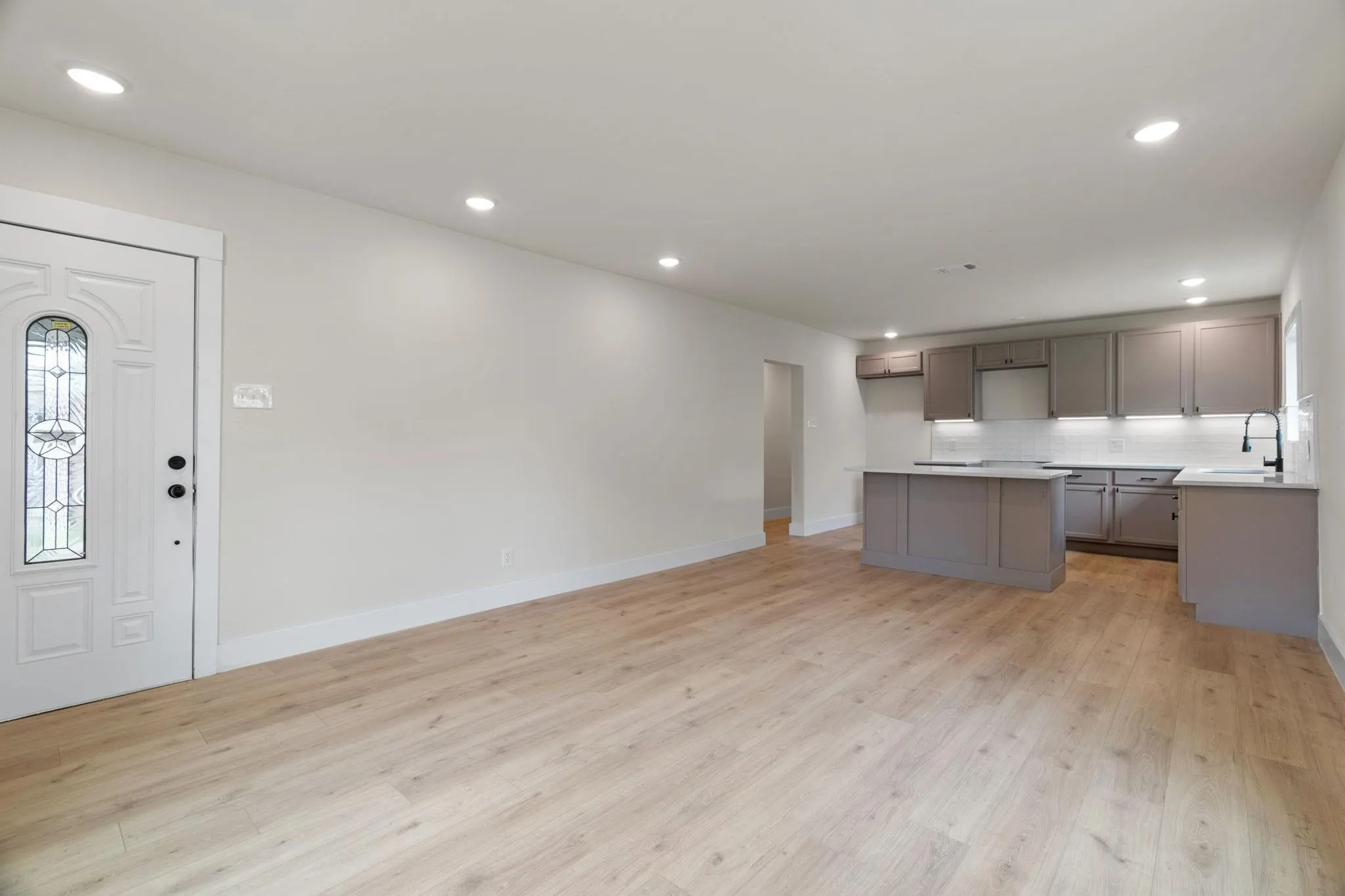 Kitchen featuring a sink, light wood-style flooring, decorative backsplash, gray cabinetry, and recessed lighting