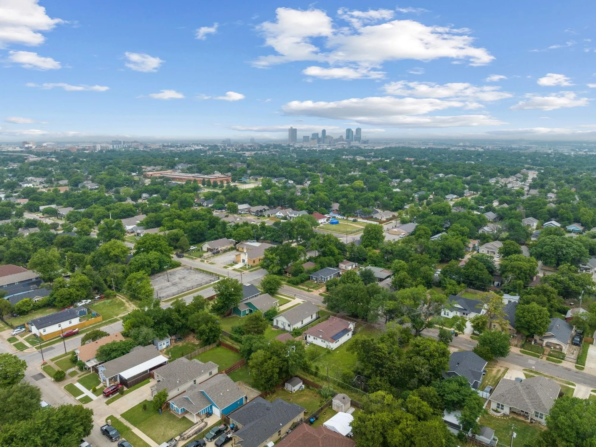 Expansive aerial perspective showcasing a residential area with dense tree canopy and distant urban skyline