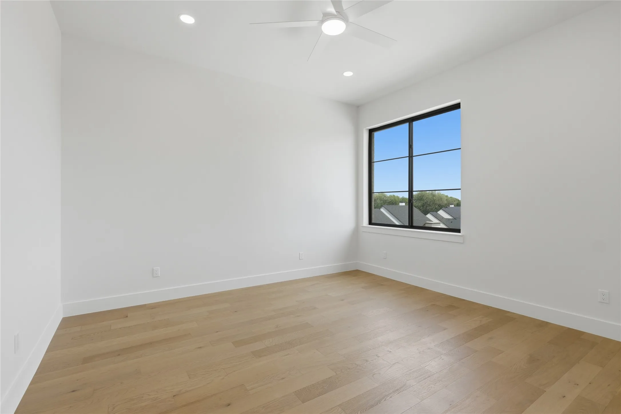 Room featuring a modern black-framed window, wood-finish flooring, recessed lighting, a ceiling fan, and crisp white walls