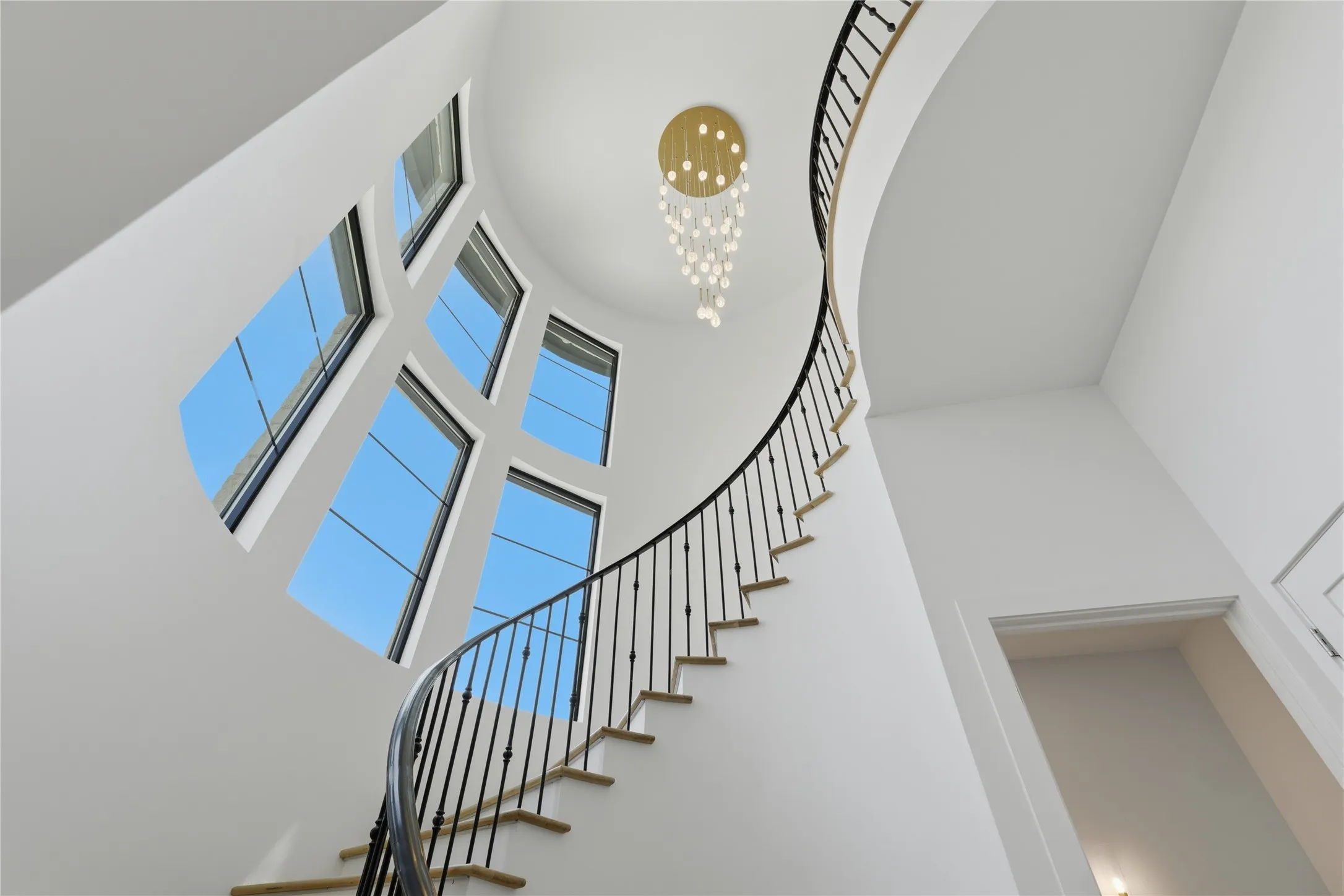 Grand curved staircase with wrought iron balusters and hardwood treads