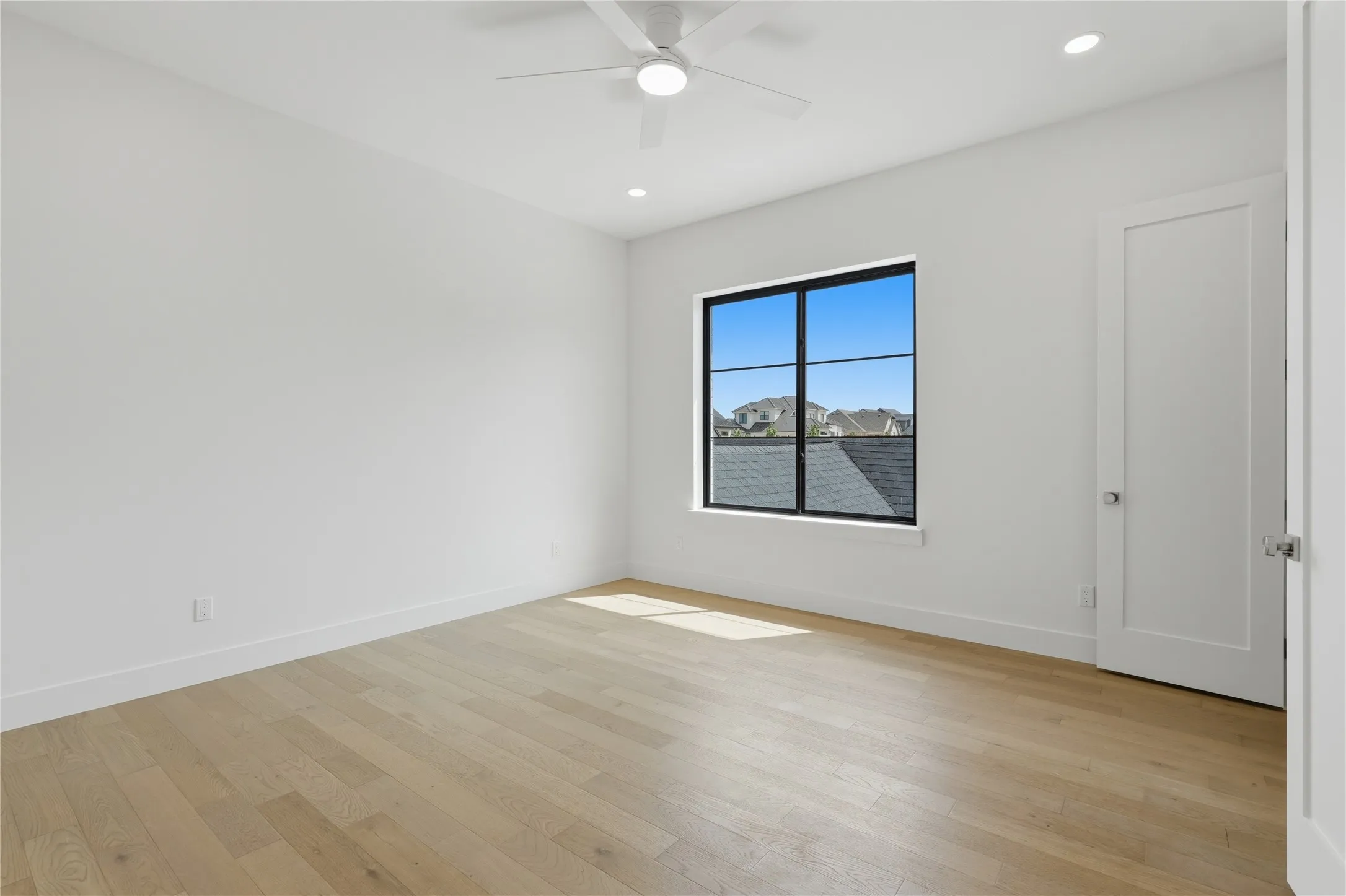 Spacious room featuring light wood-finish flooring and crisp white walls