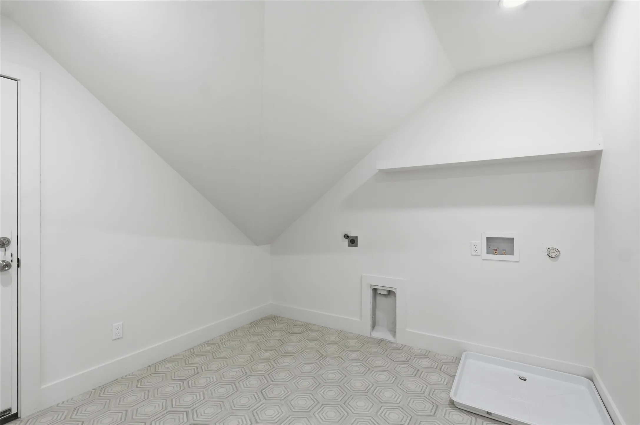 Laundry area featuring geometric patterned floor tiles, white baseboards, a utility sink rough-in, and a built-in shelf