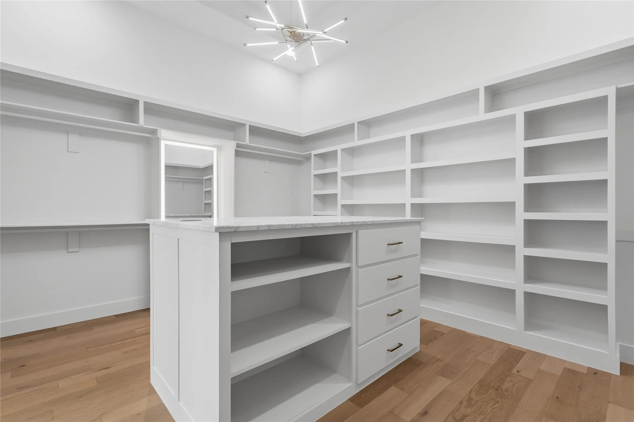 Expansive walk-in closet featuring a central island with a stone countertop and built-in drawers