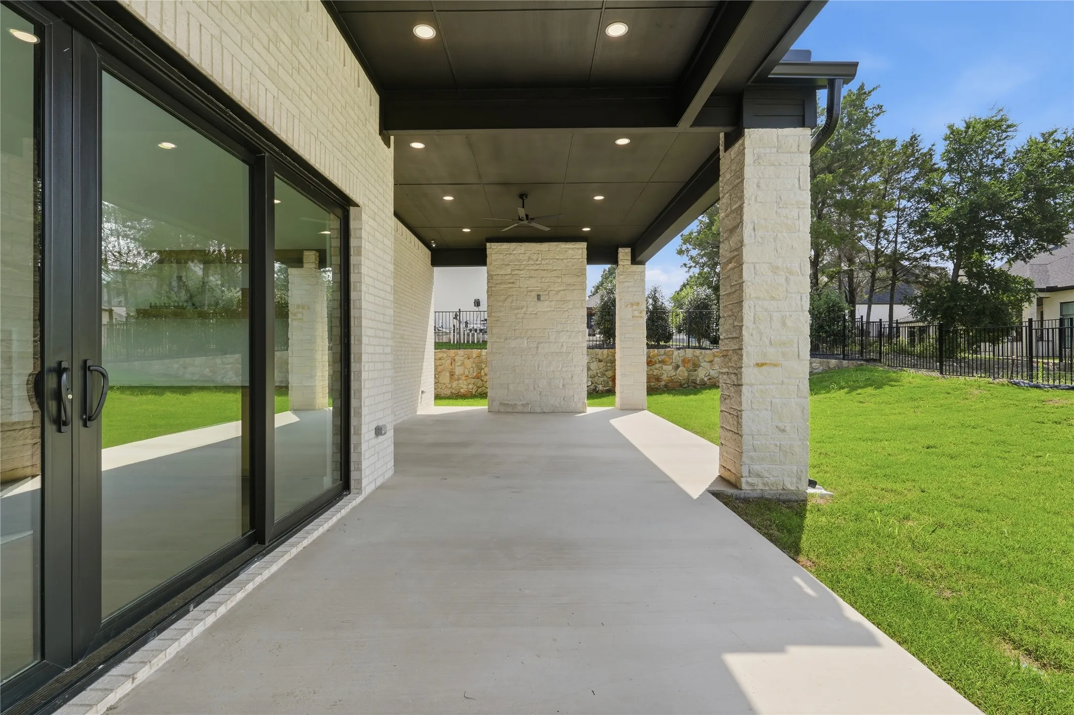 Covered patio featuring a concrete surface, stone support columns, and recessed lighting