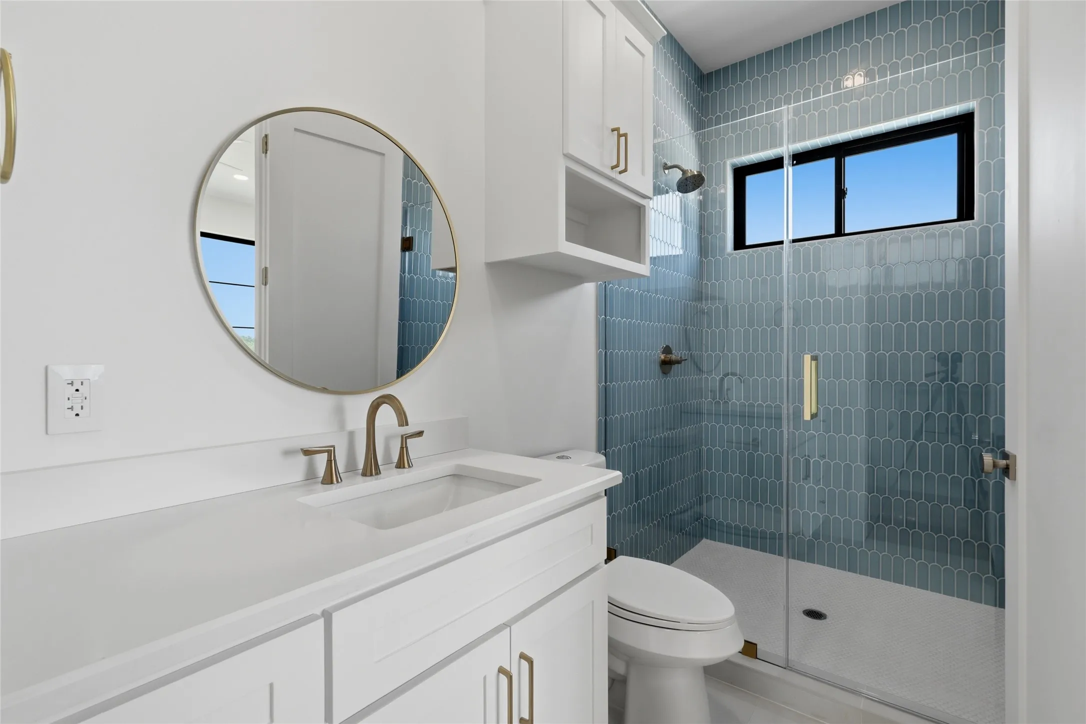 Bathroom vanity with a round framed mirror and brushed gold-tone faucet