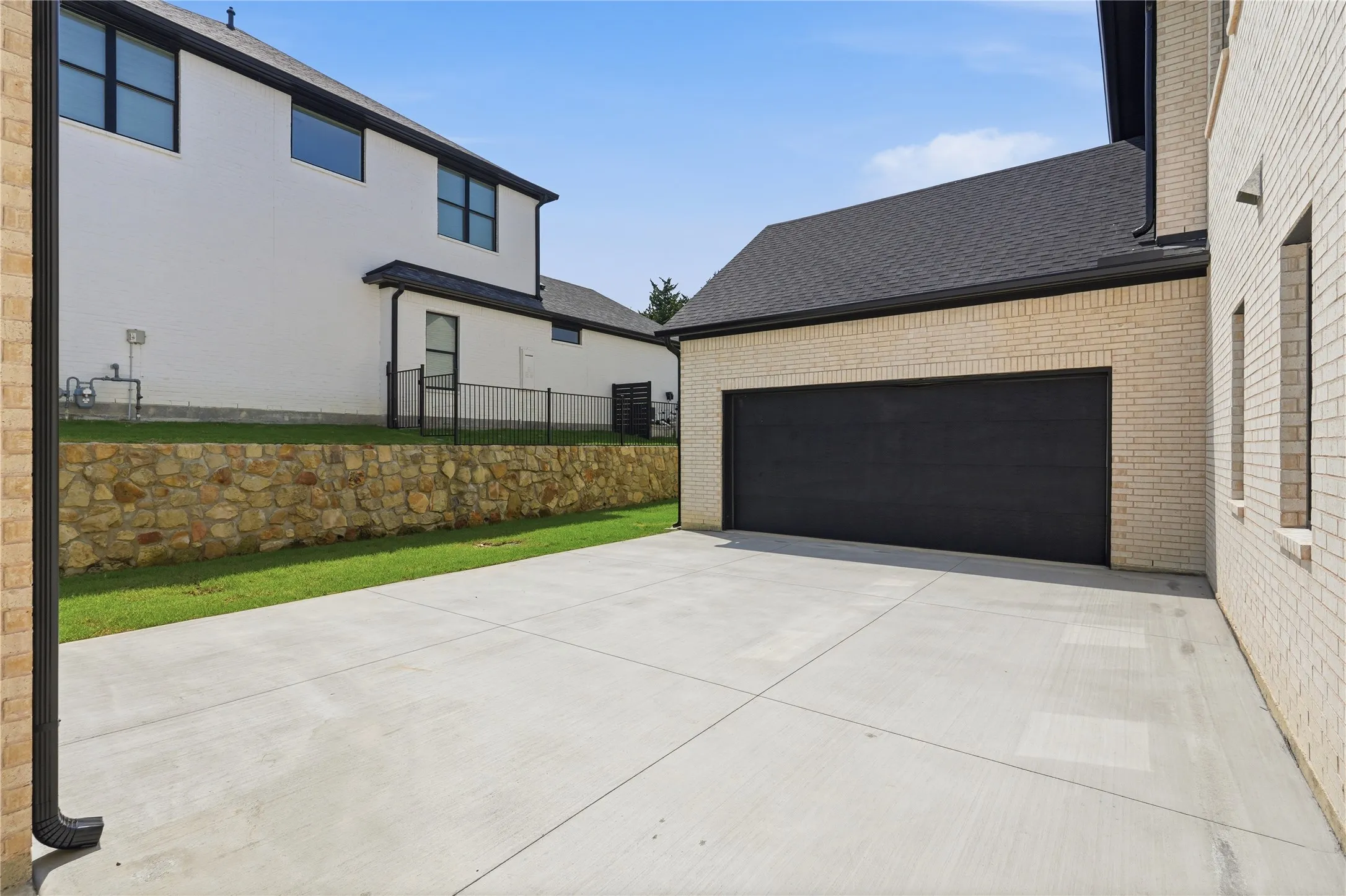 Spacious concrete driveway leading to a modern black garage door