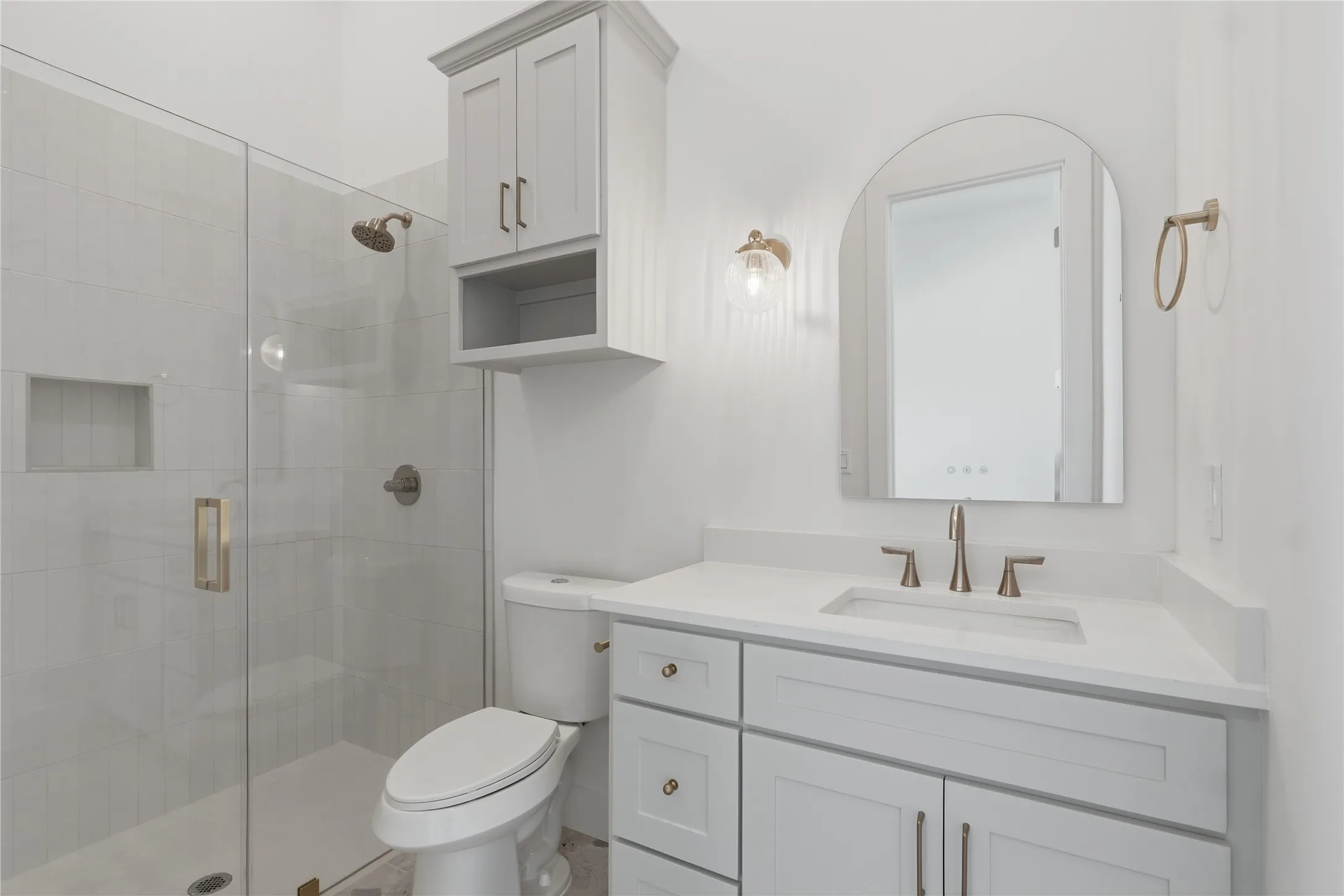 Bathroom featuring a glass-enclosed shower with tile surround, a built-in shower niche, and brushed nickel fixtures