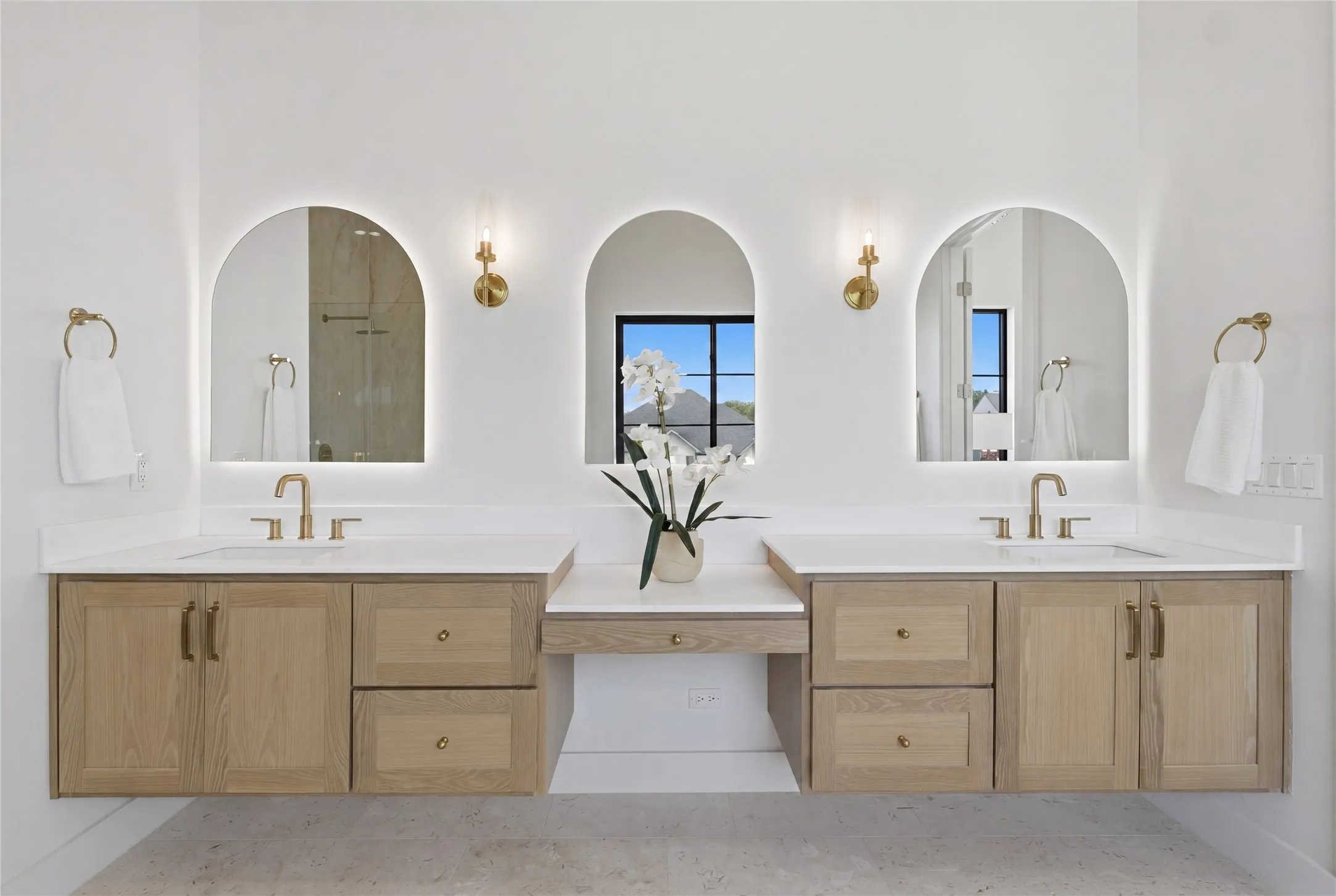 Dual floating vanities with wood-finish cabinetry and brass hardware