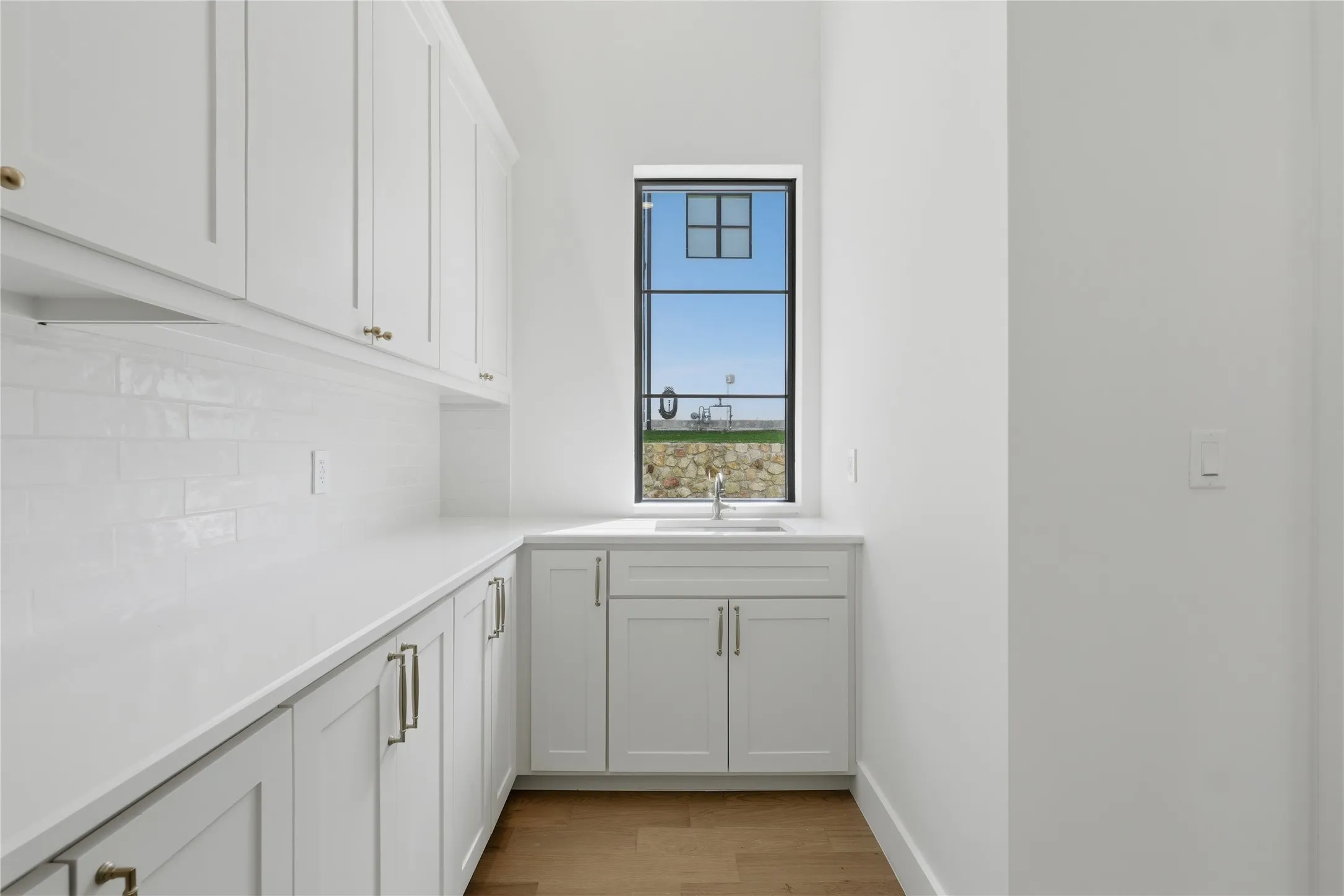 White shaker-style cabinetry with gold-tone hardware, white subway tile backsplash, and light-tone countertops