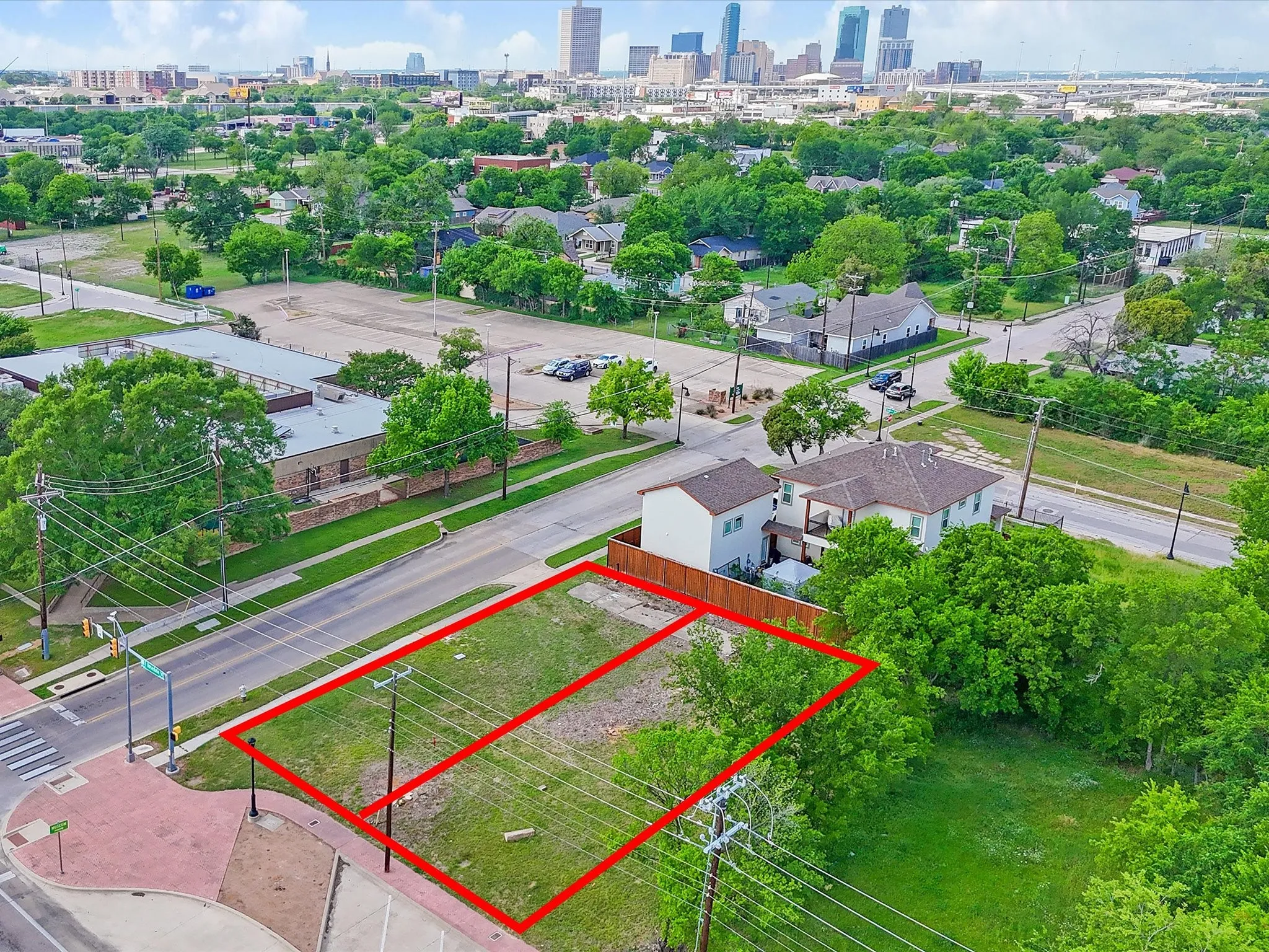 Expansive cleared lot outlined in red, featuring street frontage and mature trees at the property border