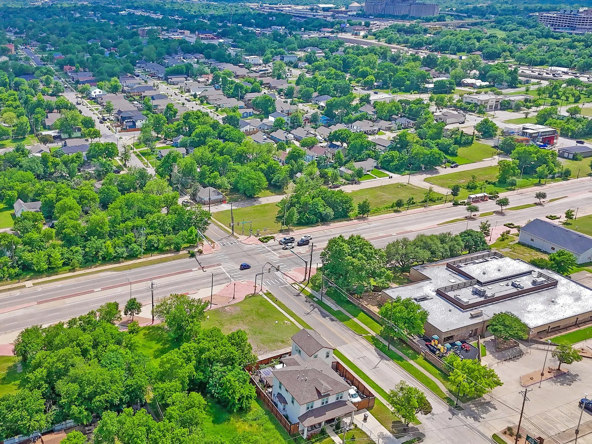 Aerial perspective showcasing a residential area with mature trees and a commercial building
