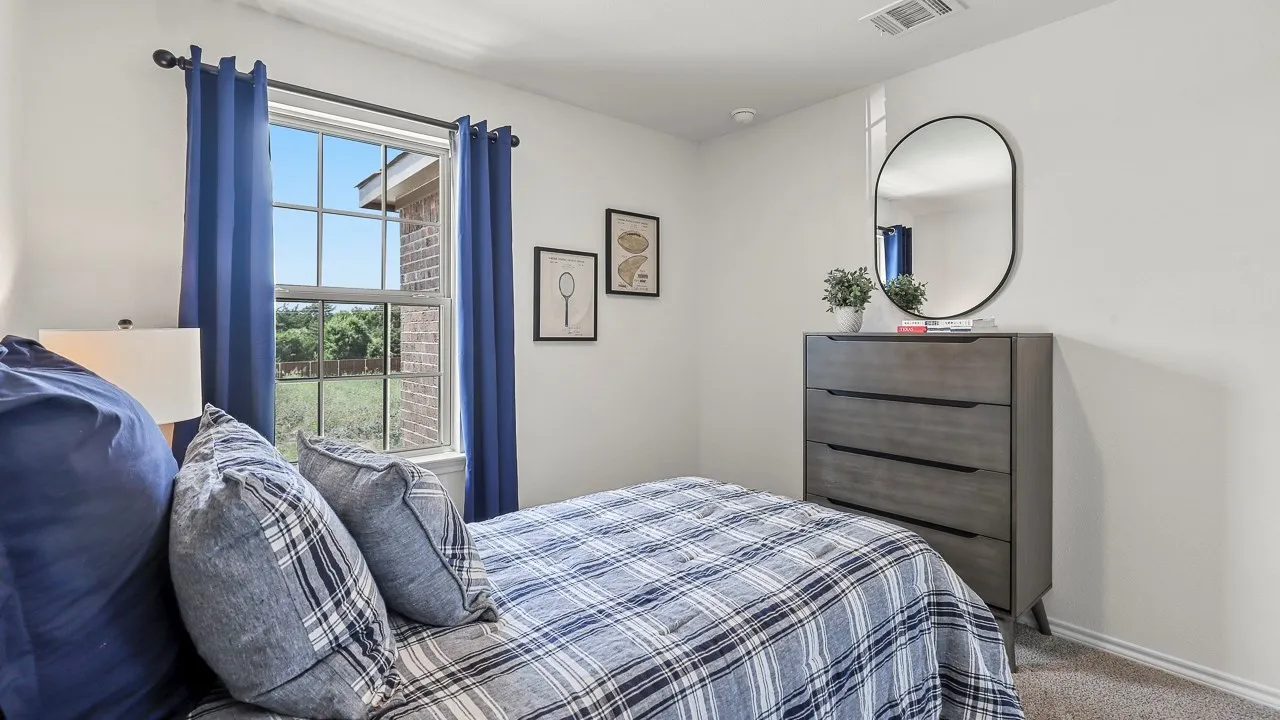 Single-hung window with grid pattern, white interior walls, gray carpet, and a wood-finish dresser with dark hardware