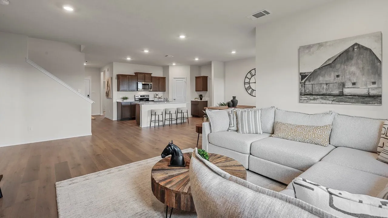 Open-concept living area featuring wood-finish flooring, recessed lighting, and a white staircase