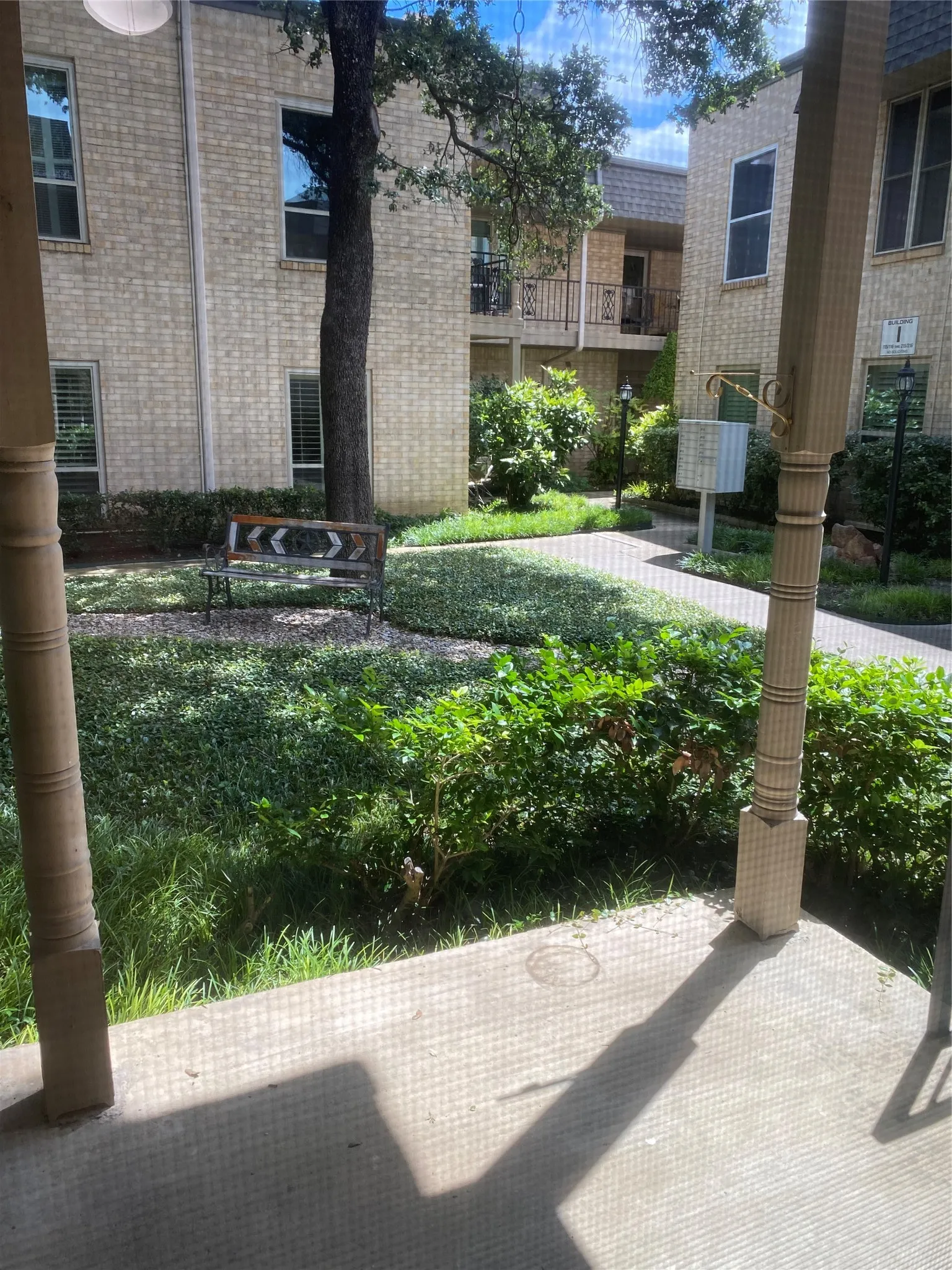 Landscaped courtyard with mature trees, brick exterior buildings, and patterned concrete walkway