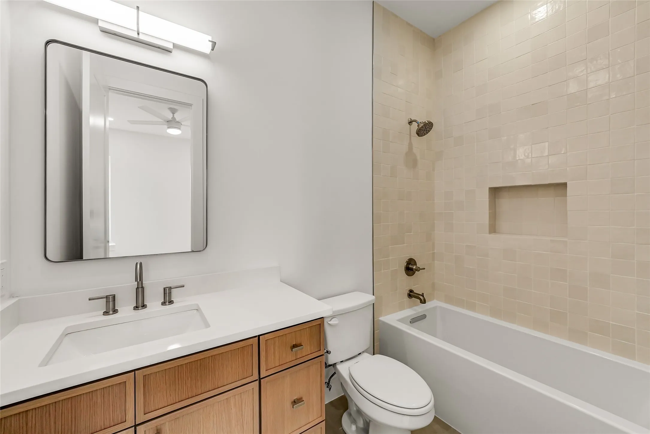Bathroom featuring a single vanity with a rectangular undermount sink, a light-toned countertop, and wood-finish cabinetry