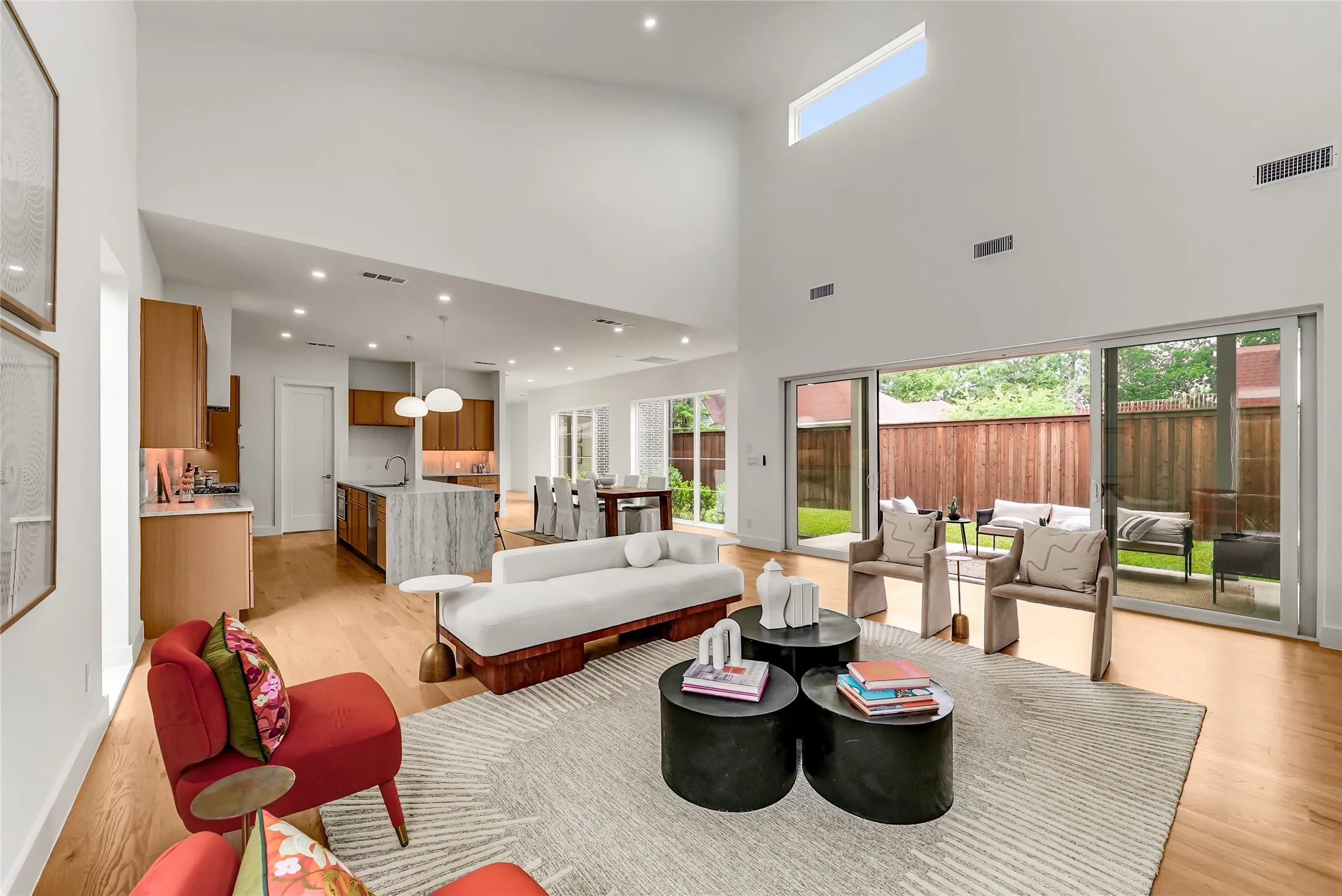 Expansive open-concept living space featuring high ceilings, wood-finish flooring, and recessed lighting