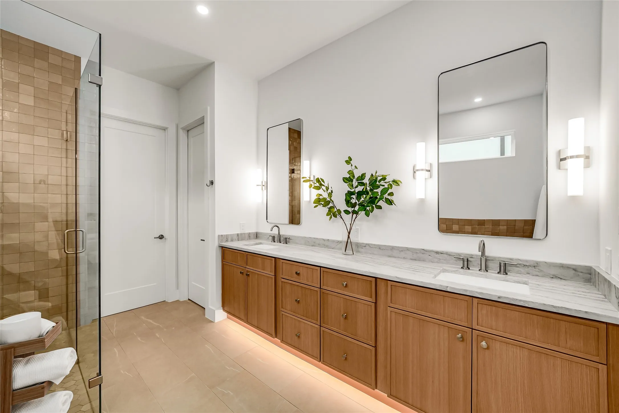 Contemporary bathroom featuring a long wood-finish vanity with dual undermount sinks, stone countertops, and rectangular mirrors