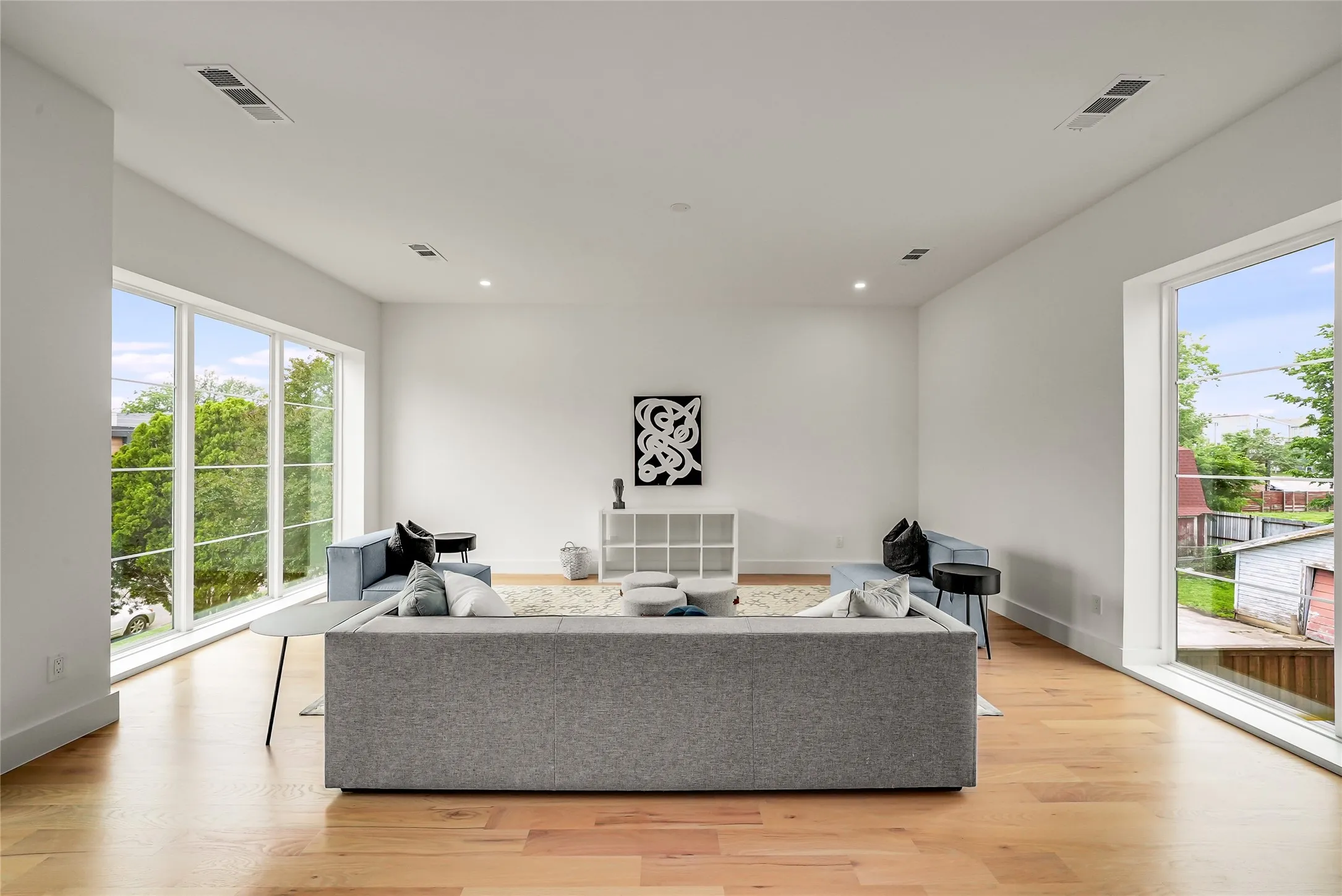 Spacious living area featuring expansive windows, recessed lighting, wood-finish flooring, white walls, and clean-line architecture