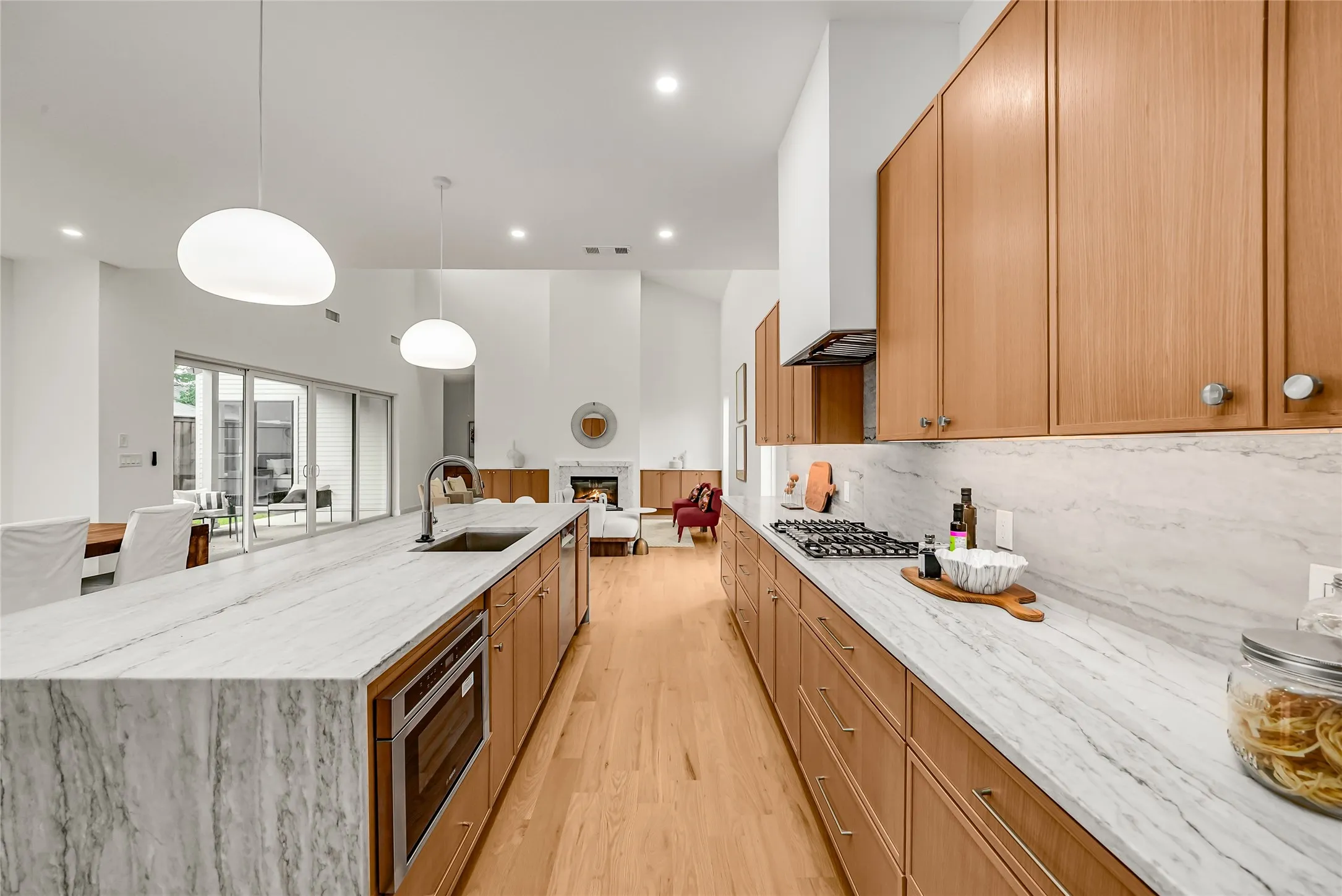 Gourmet kitchen featuring a large island with integrated sink, wood-finish cabinetry, stainless steel appliances, and light-toned countertops