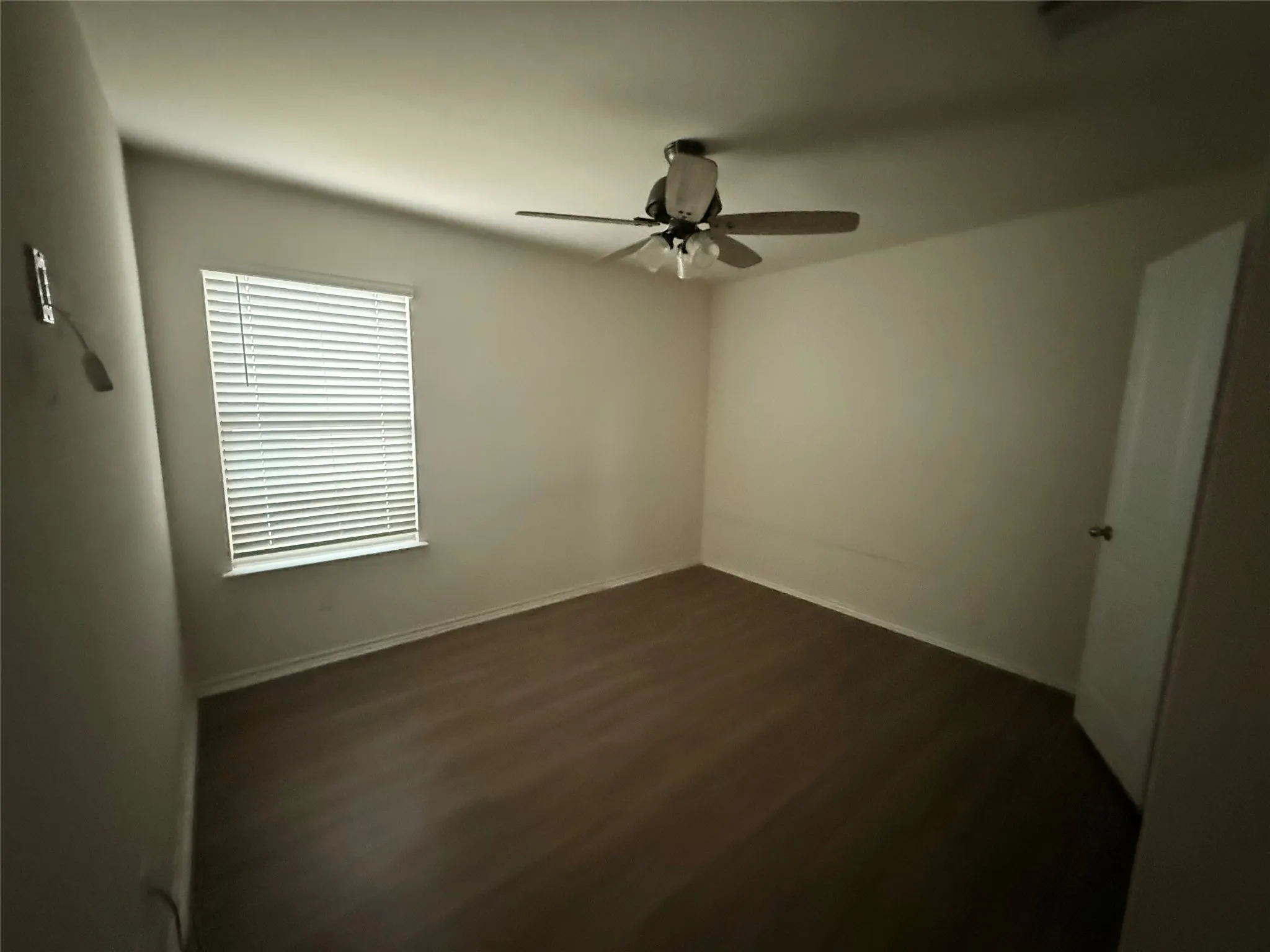 Room featuring wood-finish flooring, a window with horizontal blinds, and a ceiling fan with integrated lighting