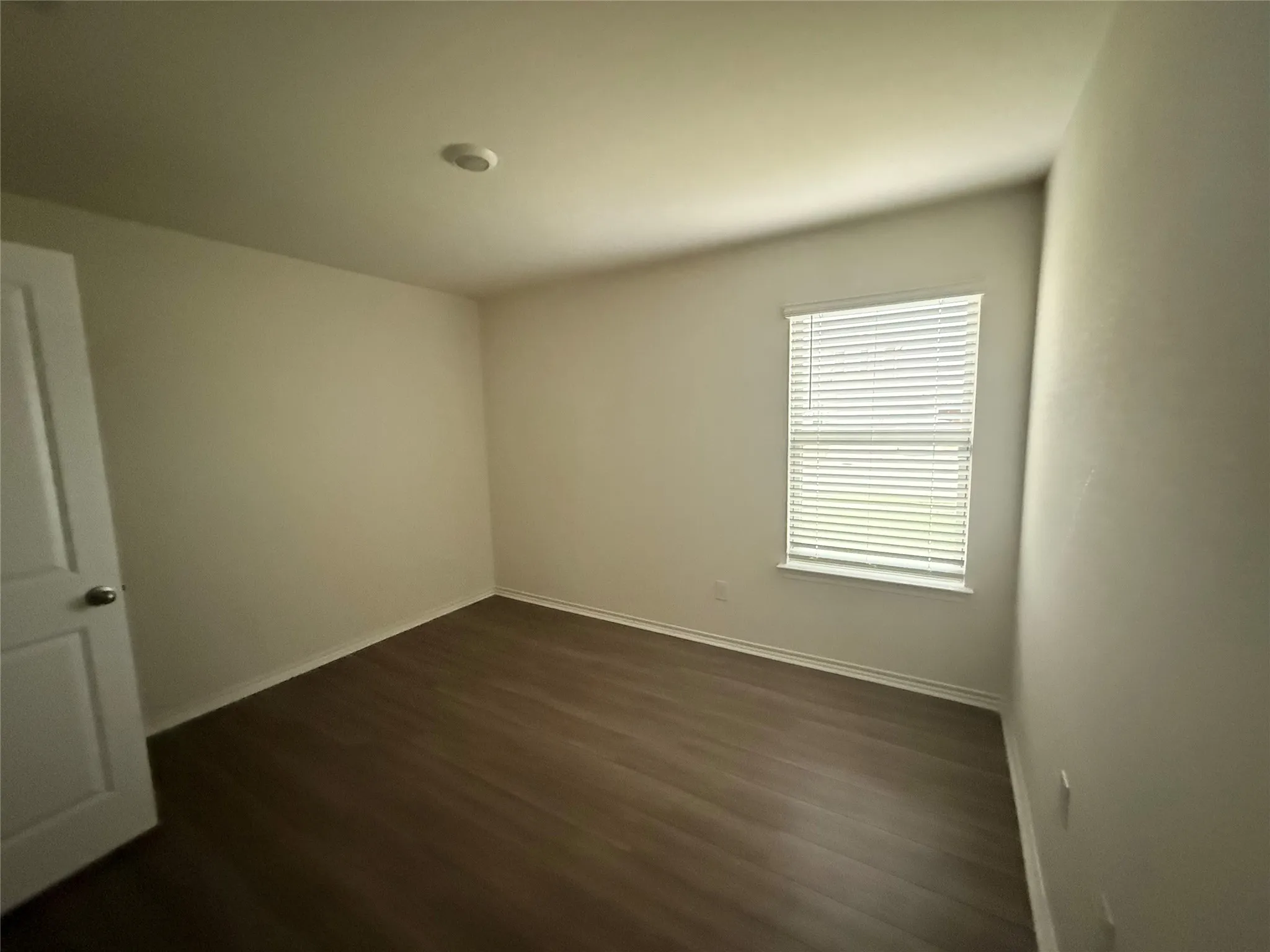 Room featuring wood-finish flooring, neutral wall tones, and white trim
