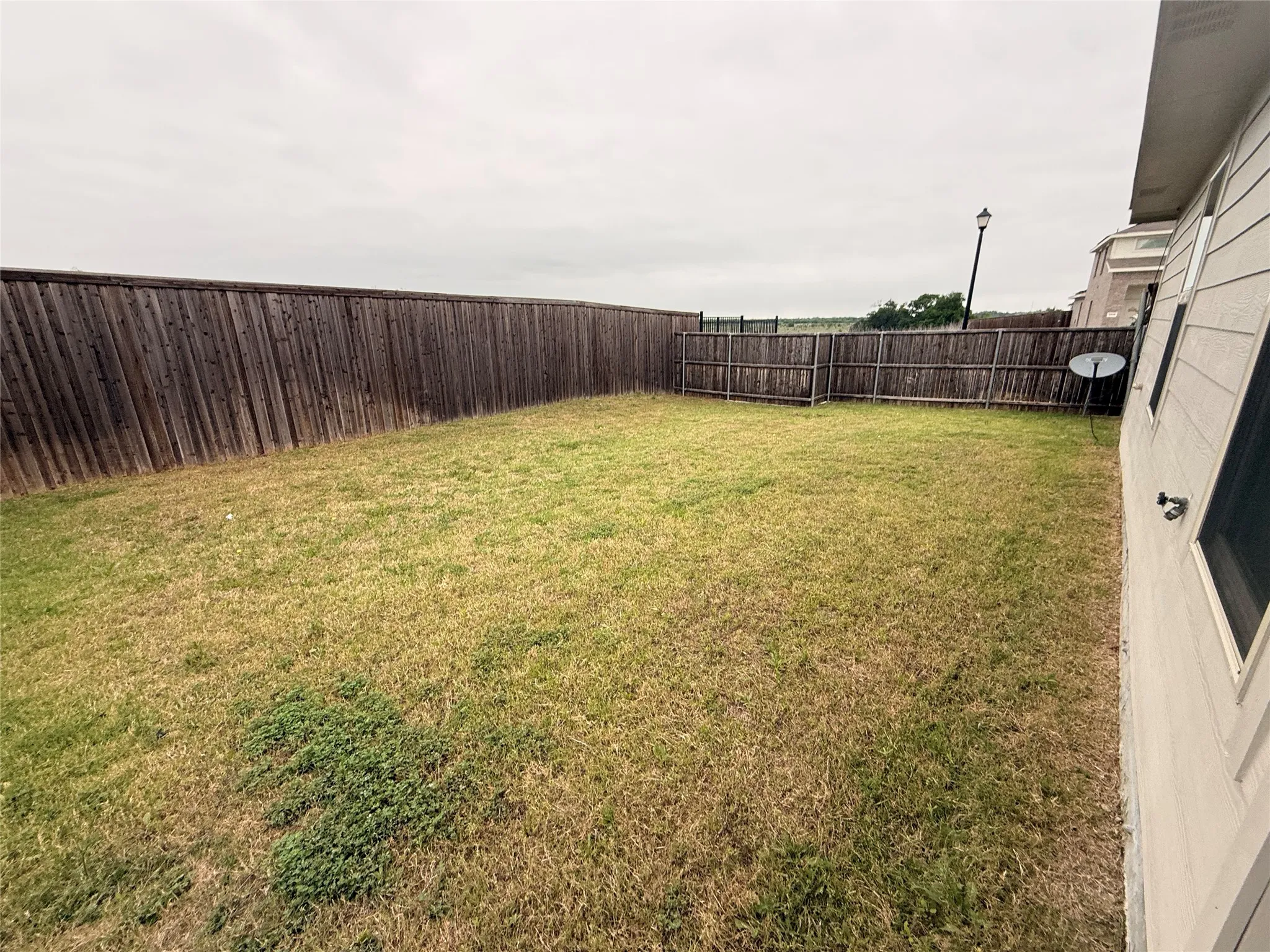 Private backyard featuring a full perimeter wooden fence and a spacious lawn area
