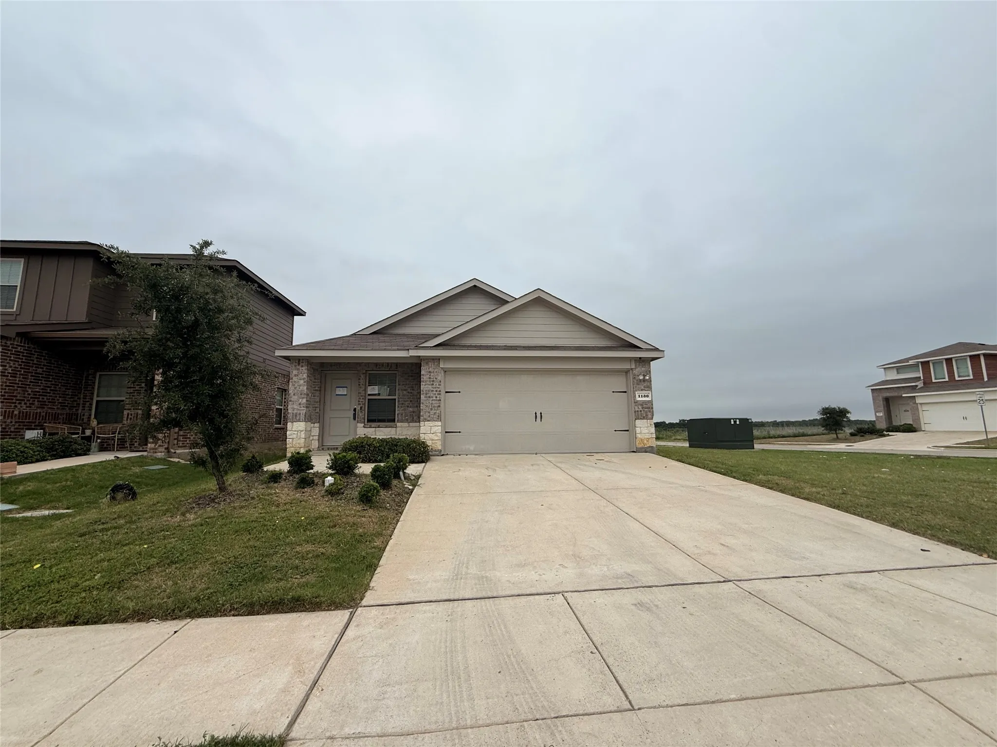 Single-story residence featuring a brick and stone facade, a two-car garage, concrete driveway, and front landscaping