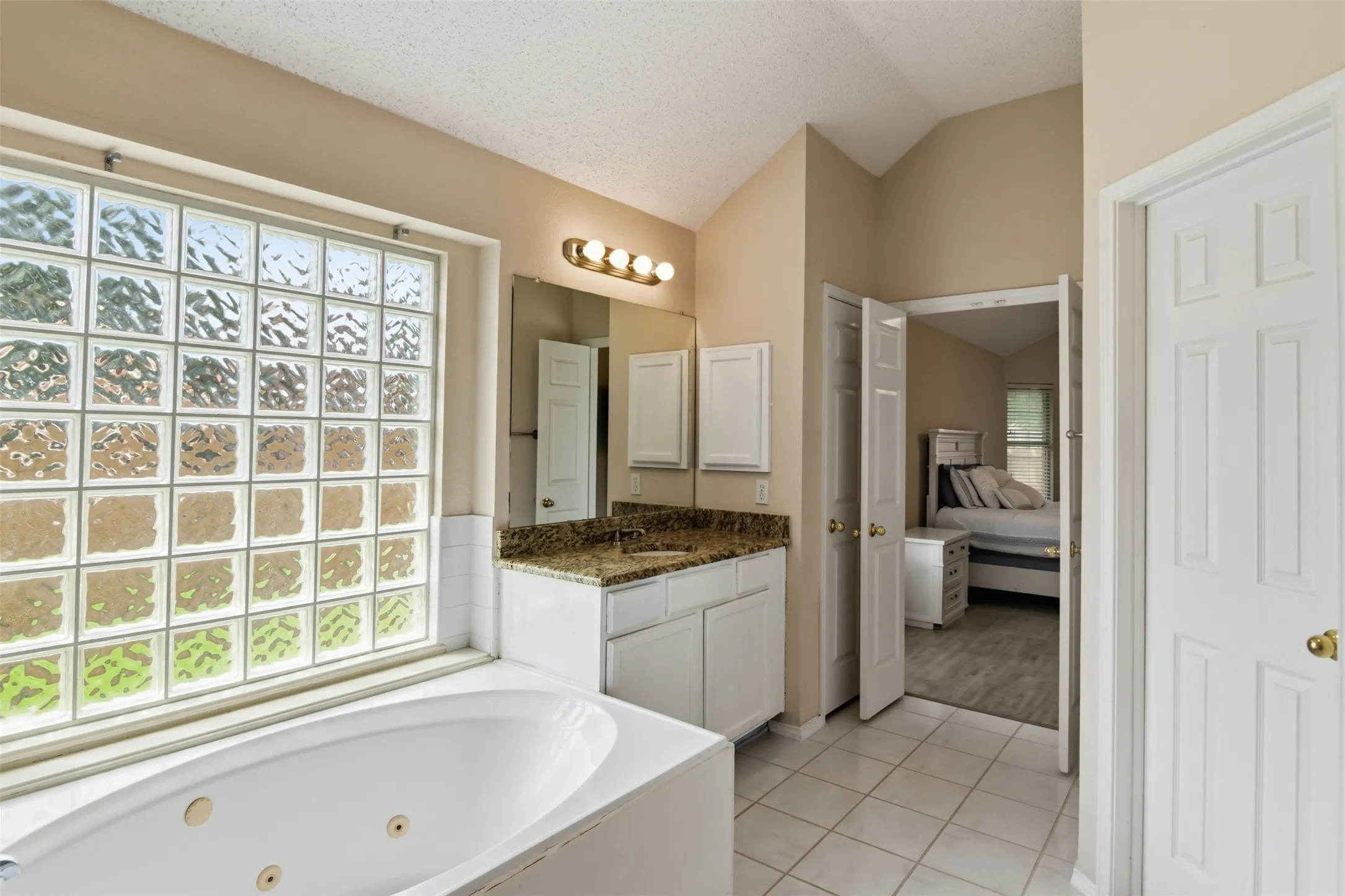 Primary bathroom with large jetted tub illuminated by glass blocks for natural light.