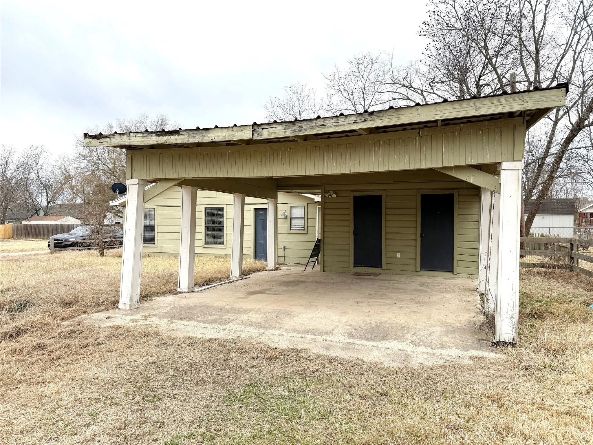 Carport structure featuring a metal roof and concrete pad, providing covered parking