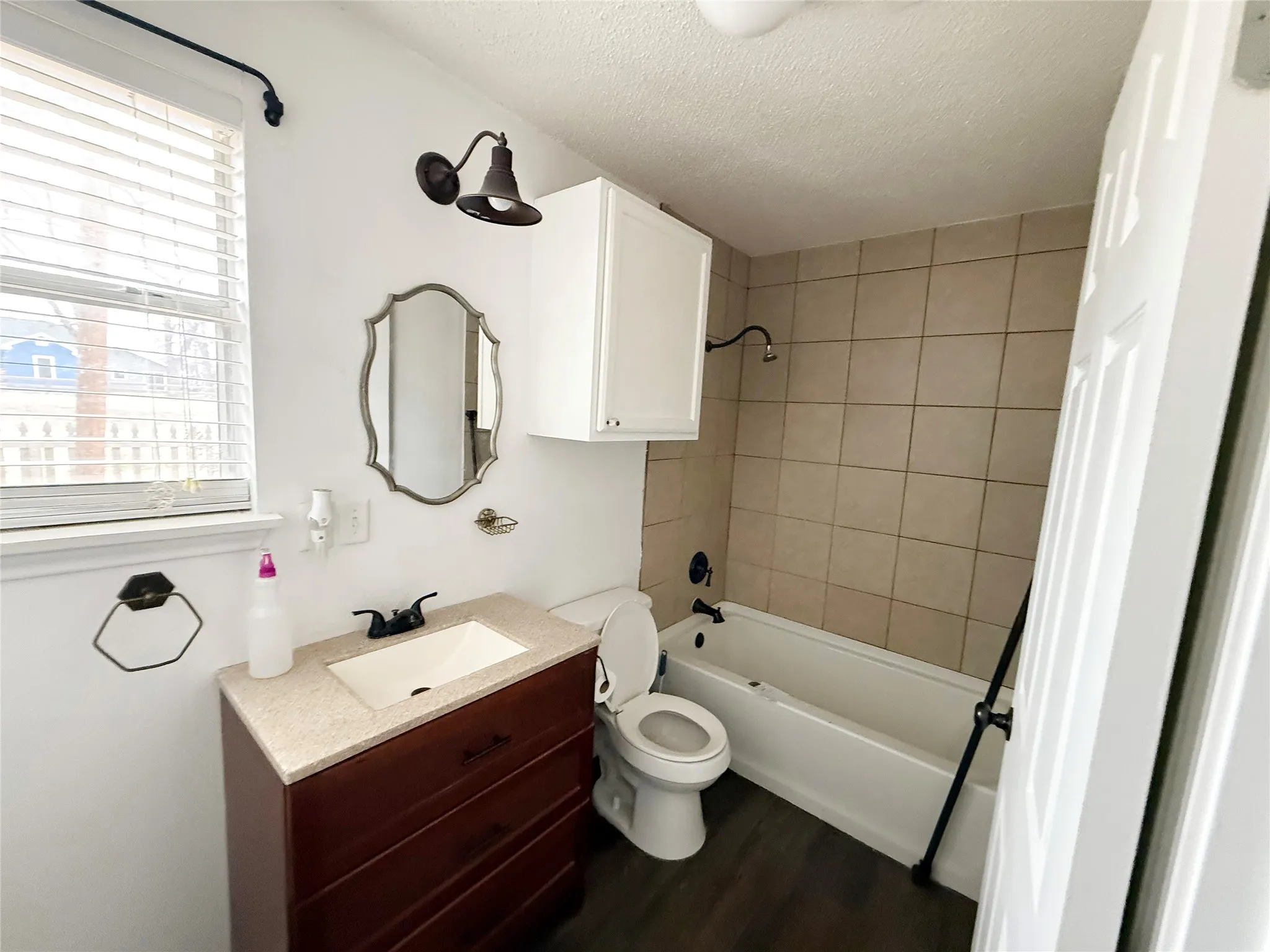 Bathroom featuring a dark wood-finish vanity with an integrated sink, a light-colored countertop, and a framed mirror