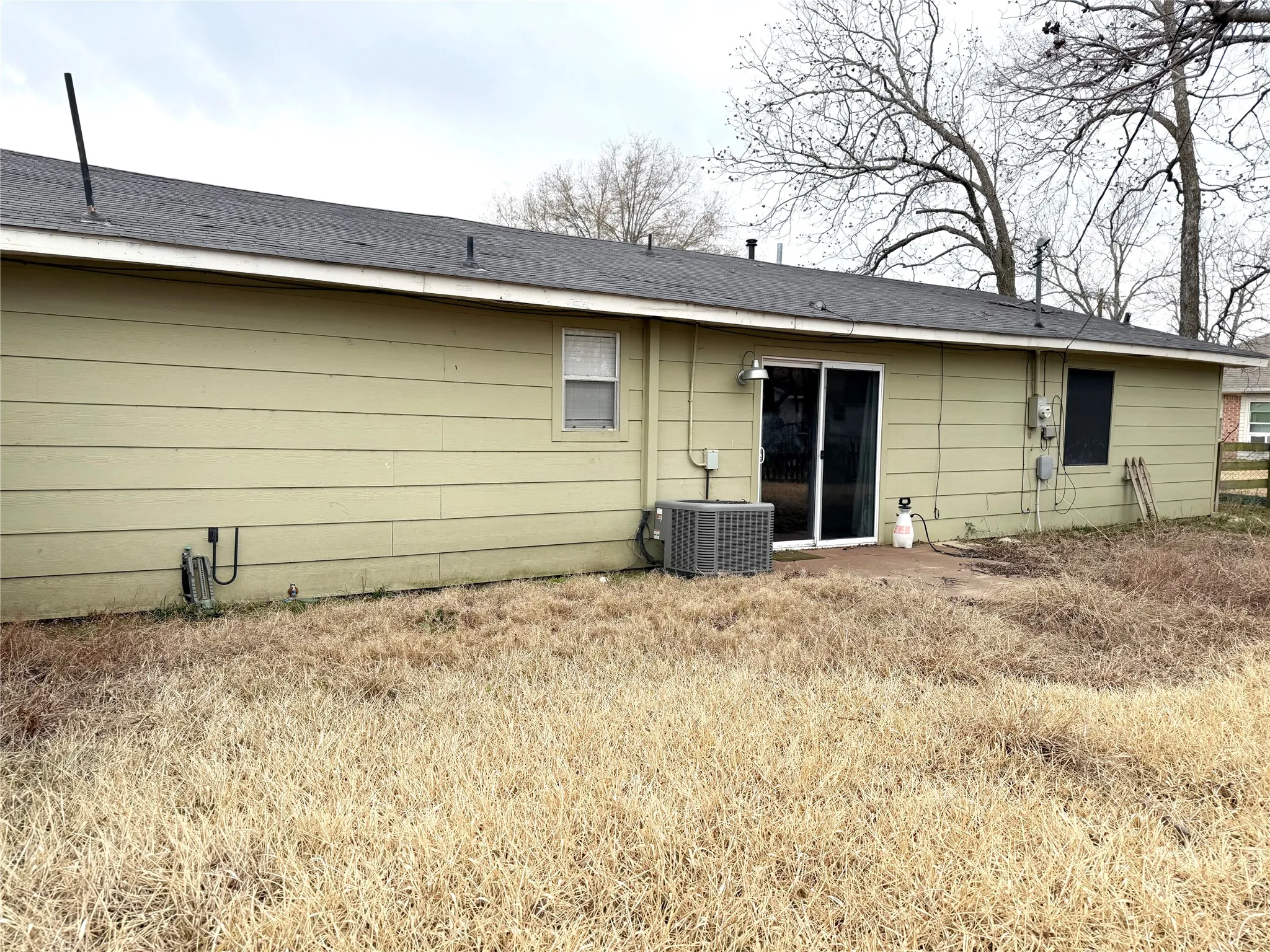 Rear exterior featuring horizontal siding, a dark shingle roof, and a sliding glass door