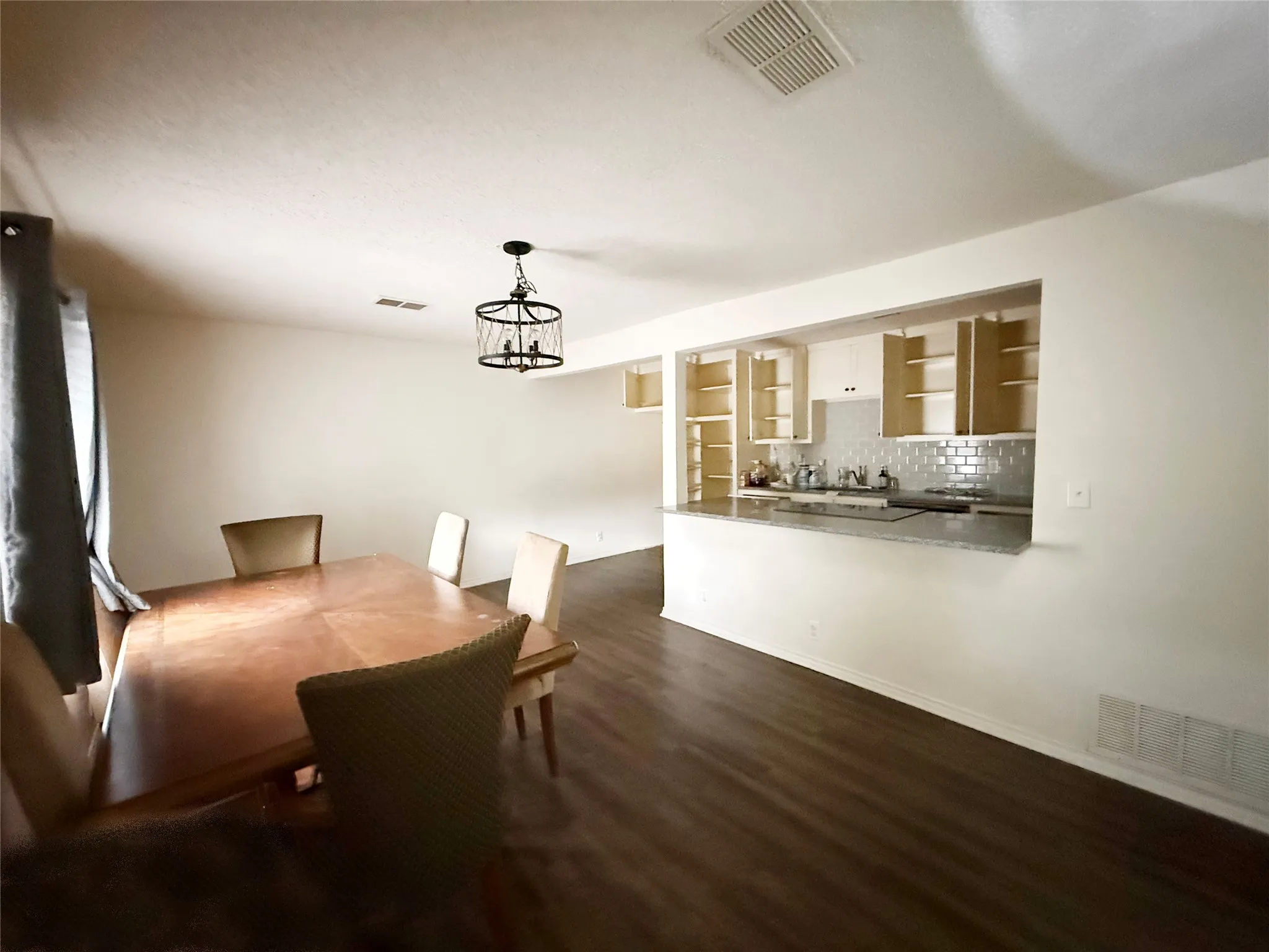 Dining area featuring dark wood-finish flooring and a contemporary caged chandelier