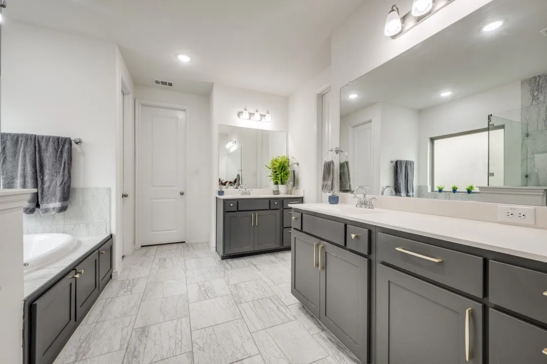 Contemporary bathroom featuring dual dark wood vanities with light countertops, undermount sinks, and chrome faucets