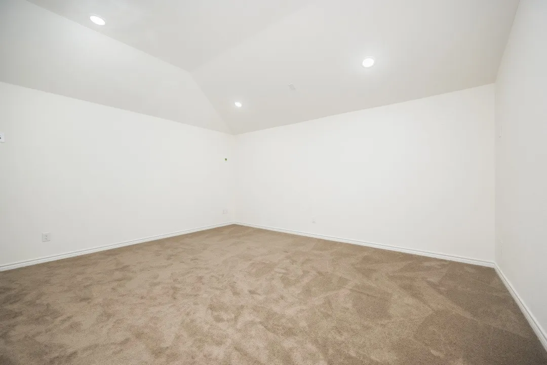 Spacious room featuring vaulted ceilings, recessed lighting, neutral wall tones, clean baseboards, and plush carpeting