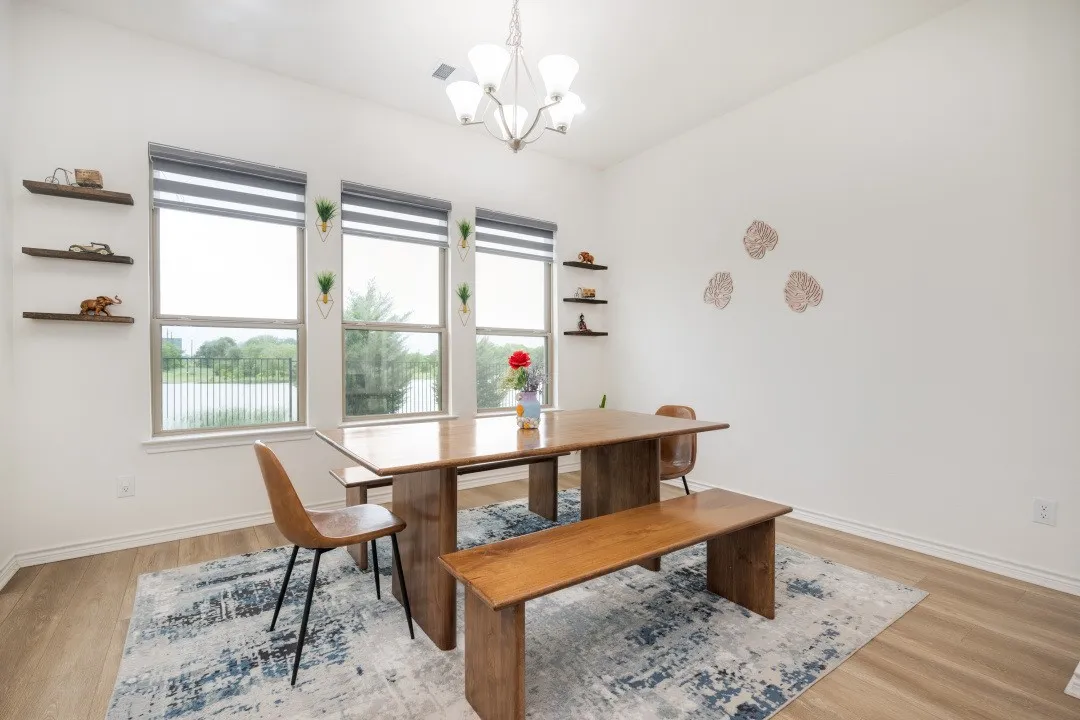 Dining area featuring abundant natural light from three windows, wood-finish flooring, a contemporary chandelier, and built-in floating shelves