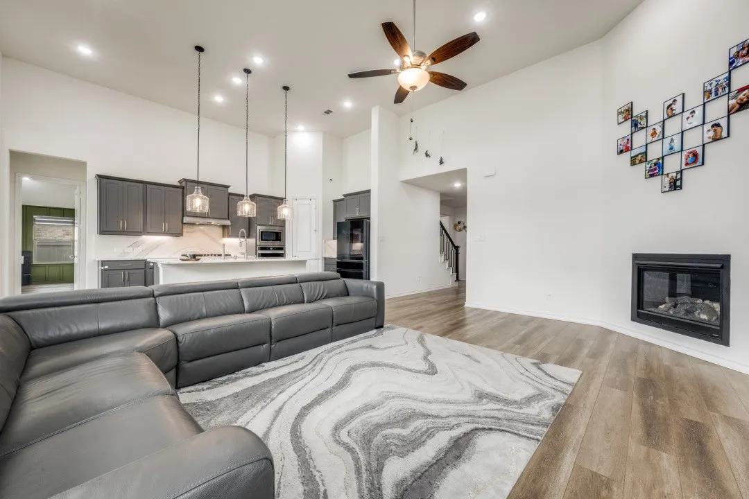 Open concept living space featuring wood-finish flooring, a contemporary fireplace, and high ceilings