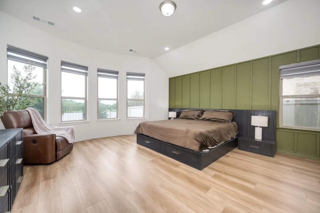 Spacious room featuring wood-finish flooring, a vaulted ceiling with recessed lighting, and a prominent accent wall with vertical paneling