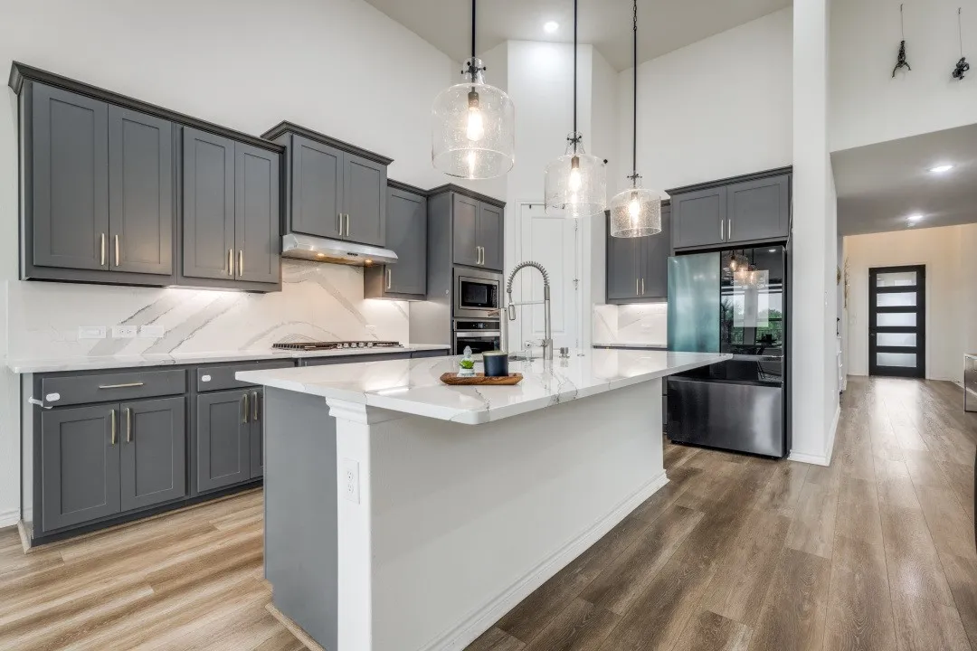 Modern kitchen featuring a large central island, gray cabinetry, integrated stainless steel appliances, and wood-finish flooring