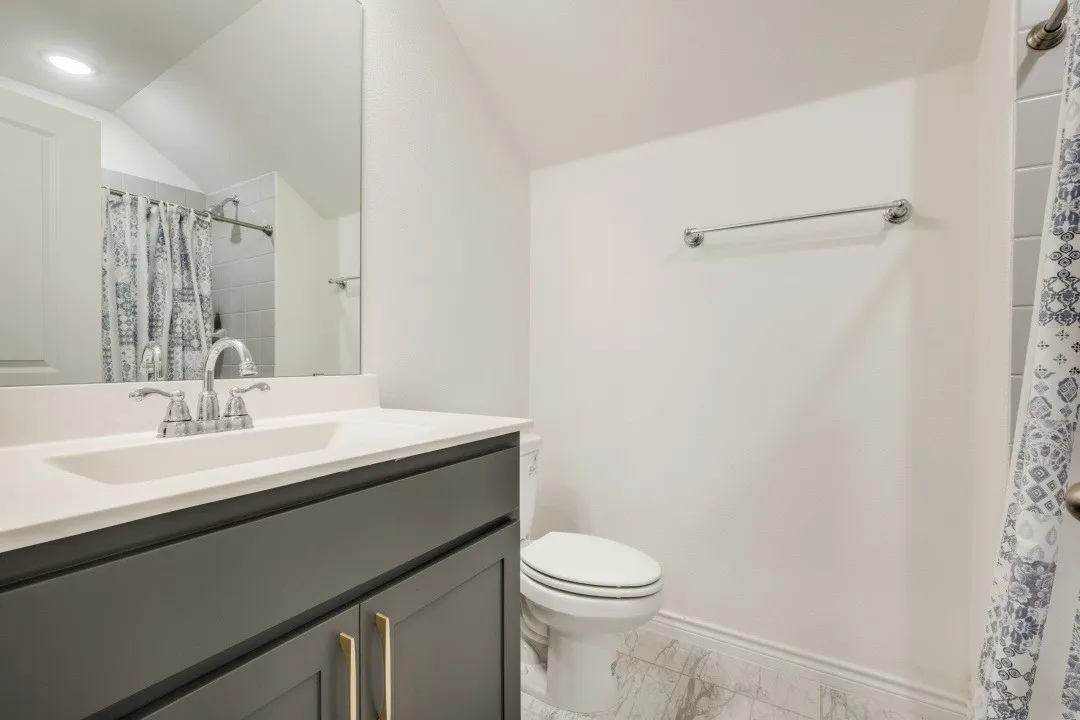 Bathroom featuring a vanity with a white countertop, undermount sink, and dark cabinetry with gold-toned hardware