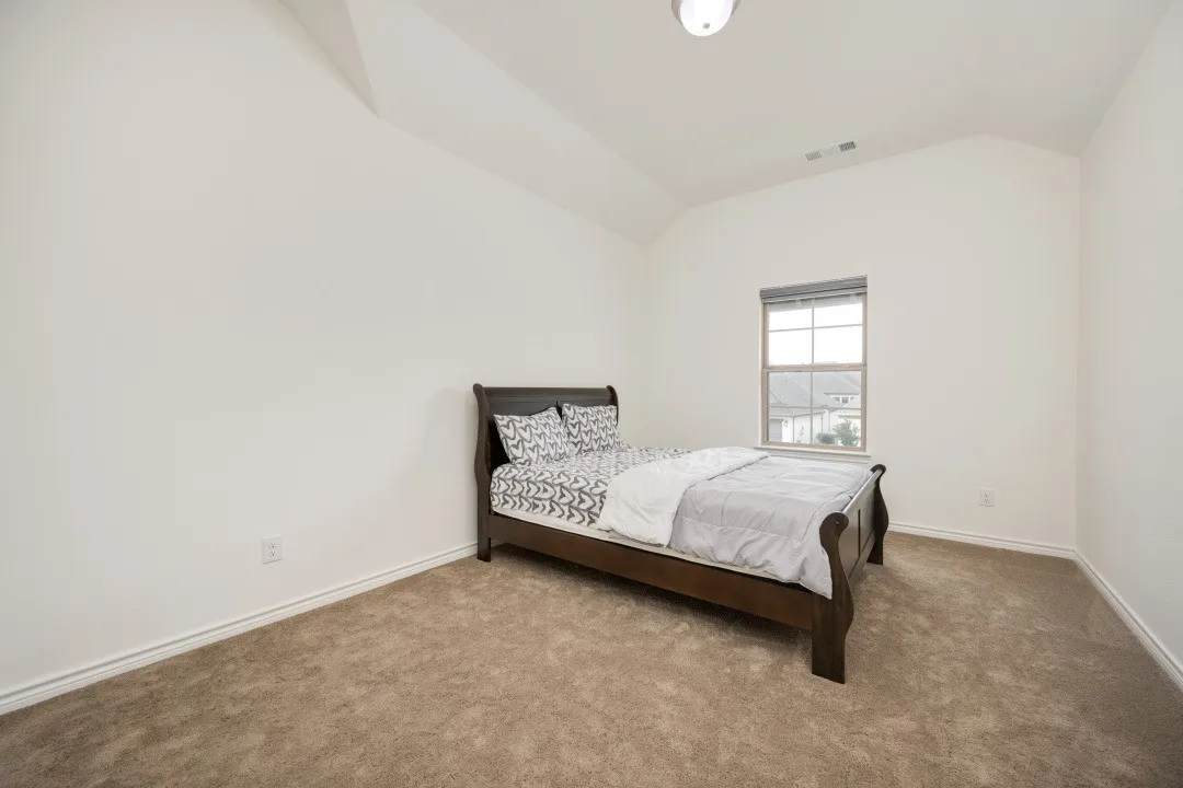 Room featuring a single window with blinds, carpeted flooring, and a vaulted ceiling