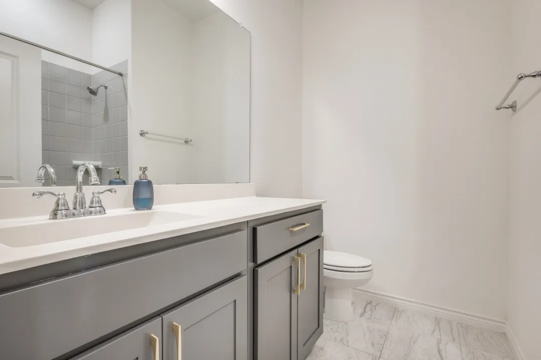 Bathroom featuring a vanity with gray cabinetry, a white countertop, and an integrated sink with a chrome faucet