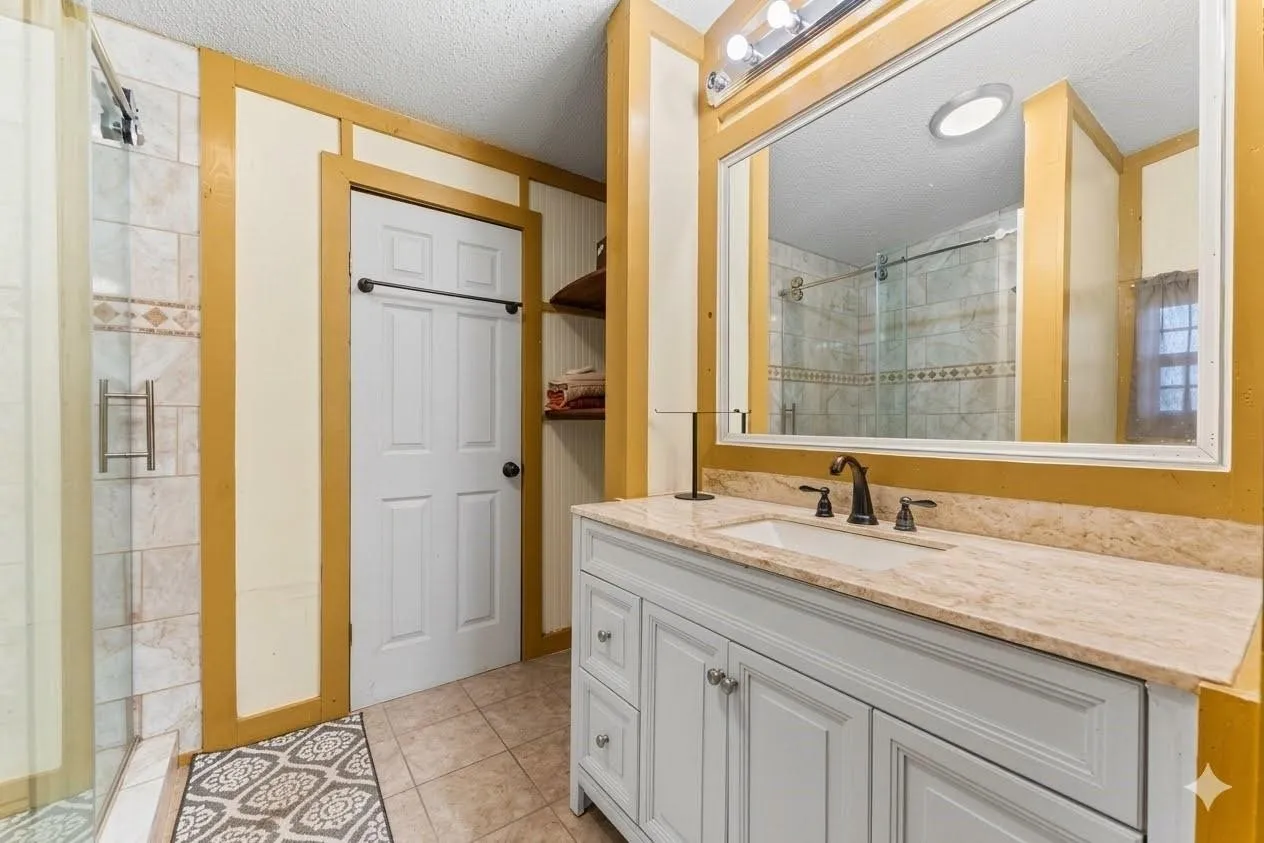 White wood-finish vanity with an integrated sink, polished countertop, and bronze-finish faucet