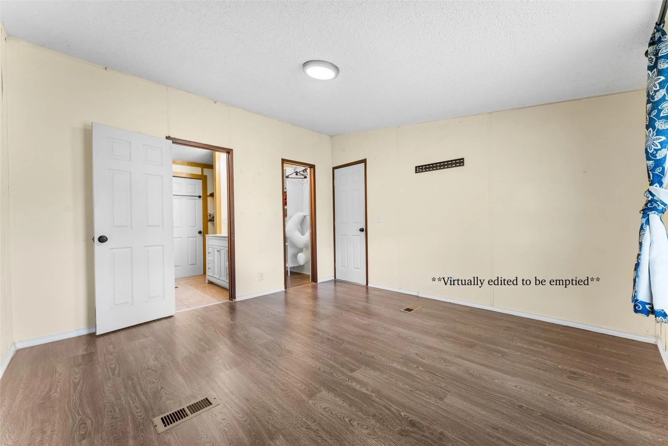 Wood-finish flooring, white paneled doors, ceiling-mounted light fixture, and light-toned walls
